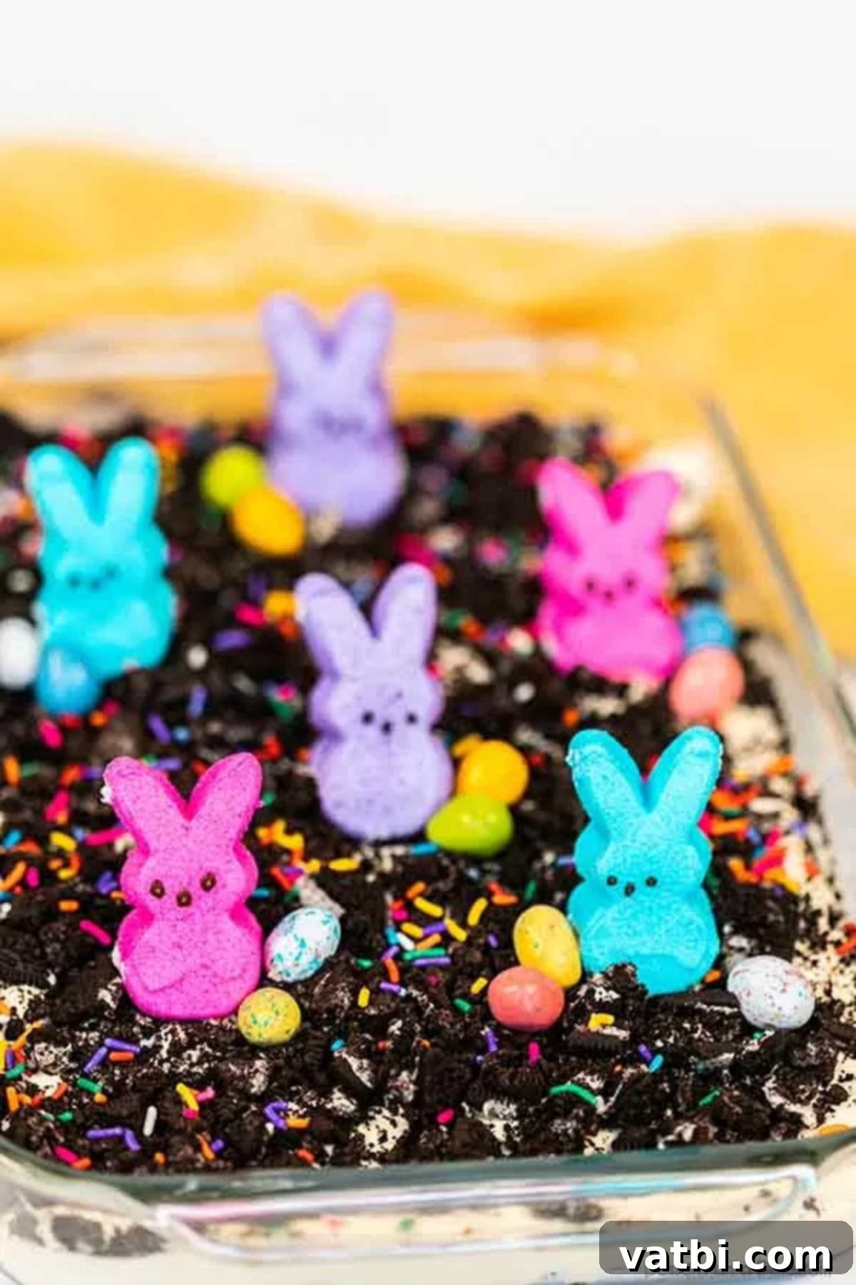 Easter dirt cake is an easy and delicious no bake treat perfect for dessert on Easter. This fun dessert is decorated with Easter peeps, candy and more. Festive Easter Dirt Cake in a clear baking dish, showcasing layers of Oreos, cream cheese filling, and vibrant Easter candy.