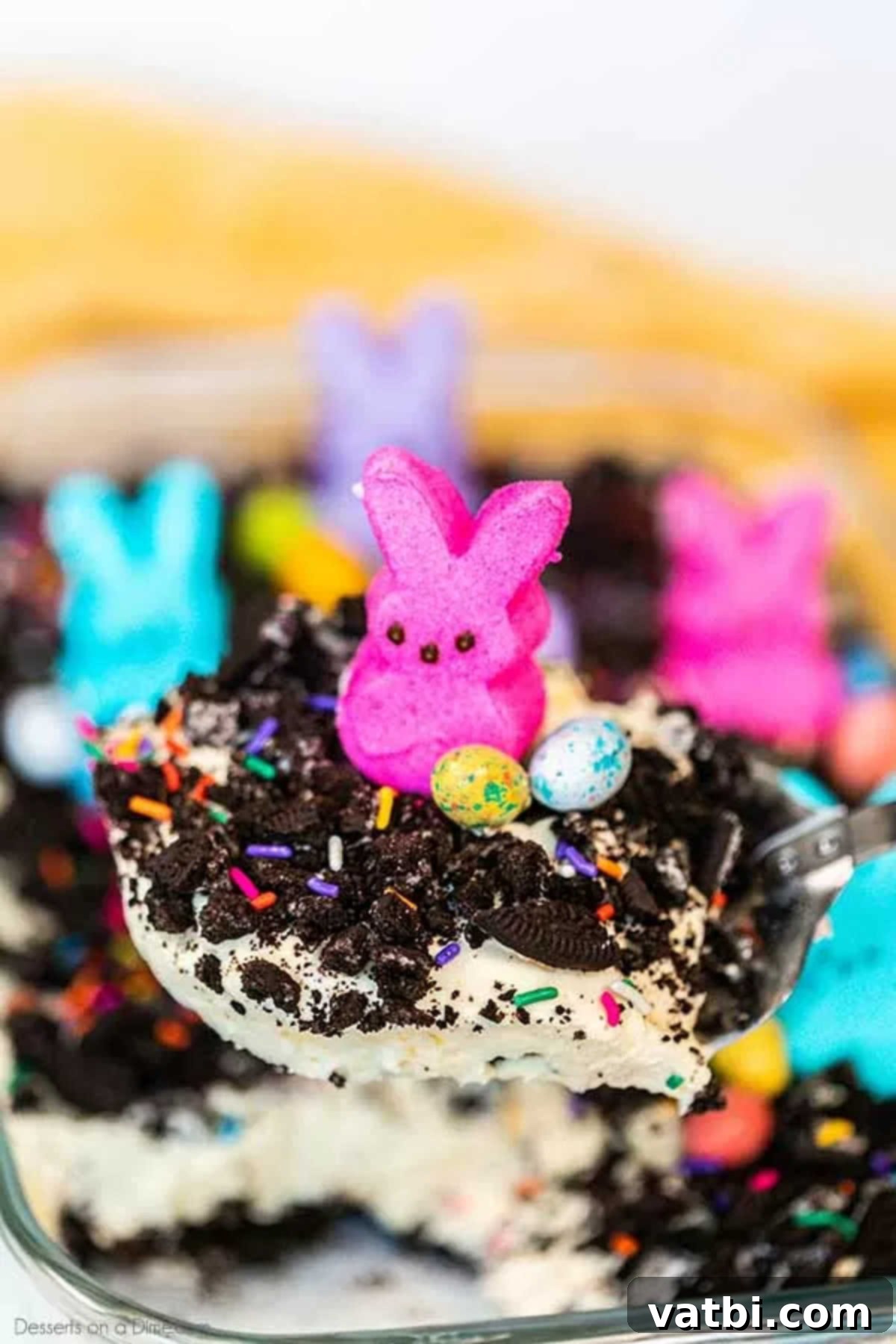 Easter dirt cake is an easy and delicious no bake treat perfect for dessert on Easter. This fun dessert is decorated with Easter peeps, candy and more. A serving of Easter dirt cake being scooped out of the pan with a spoon, showing the distinct layers.