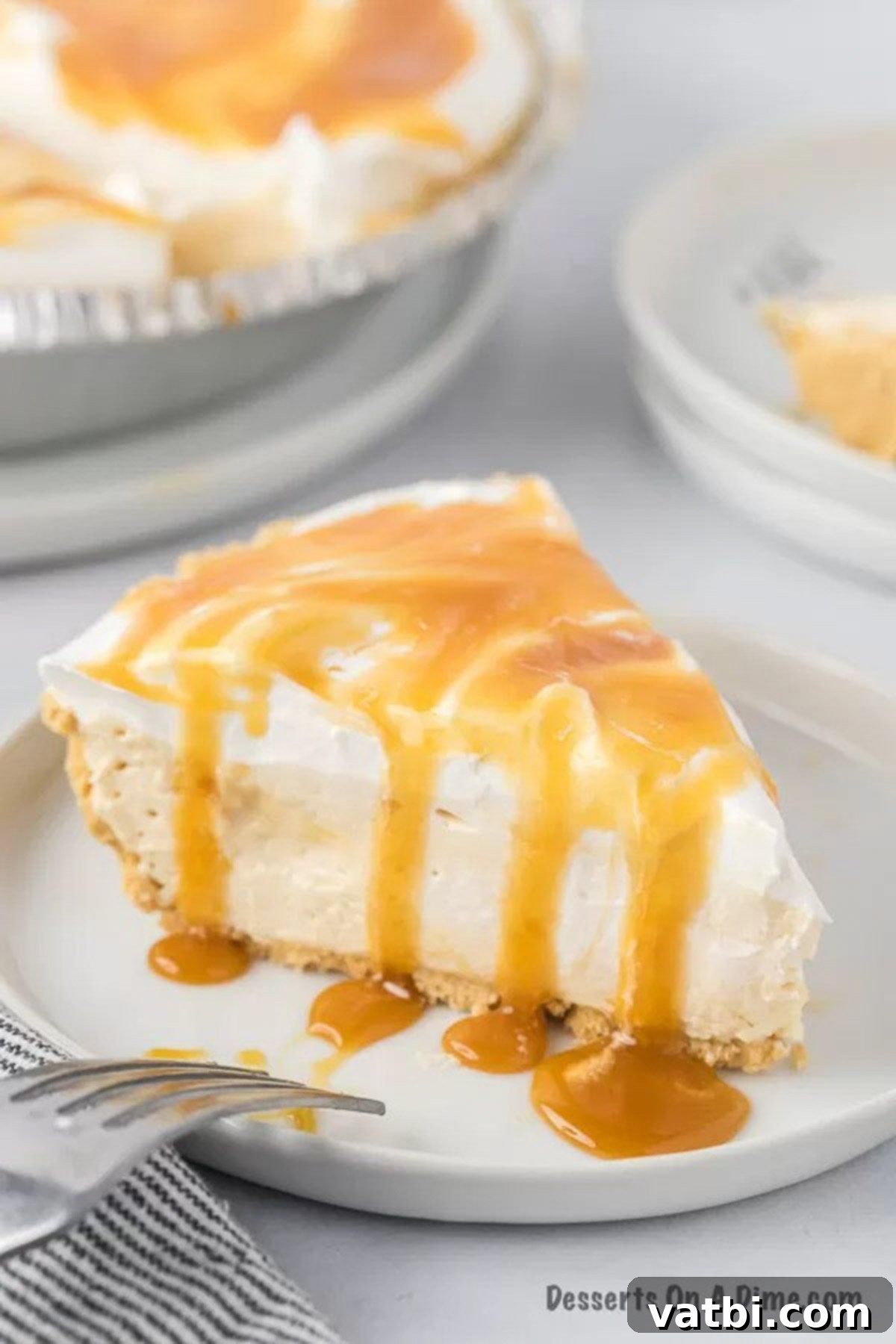 Irresistible Salted Caramel Pie 10 A slice of no bake salted caramel pie, showing the layers of crust, creamy filling, whipped topping, and caramel drizzle.