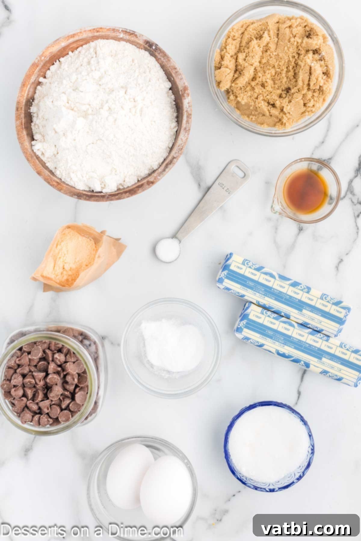 Irresistibly Soft Chocolate Chip Pudding Cookies 3 Assorted ingredients for chocolate chip pudding cookies, including butter, sugars, eggs, vanilla extract, pudding mix, and chocolate chips, laid out on a table.
