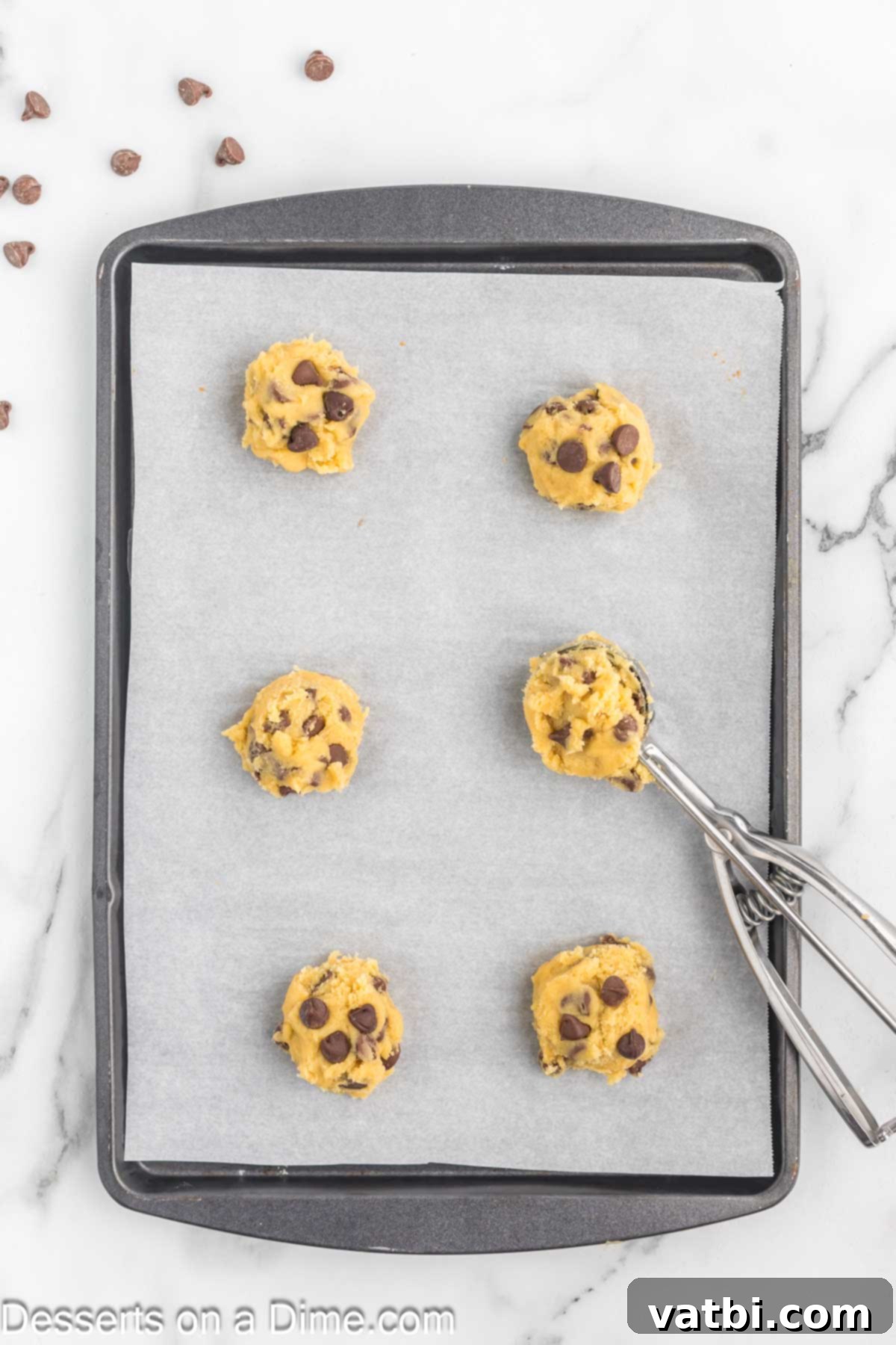 Irresistibly Soft Chocolate Chip Pudding Cookies 8 Scoops of chocolate chip cookie dough evenly spaced on a parchment-lined baking sheet.