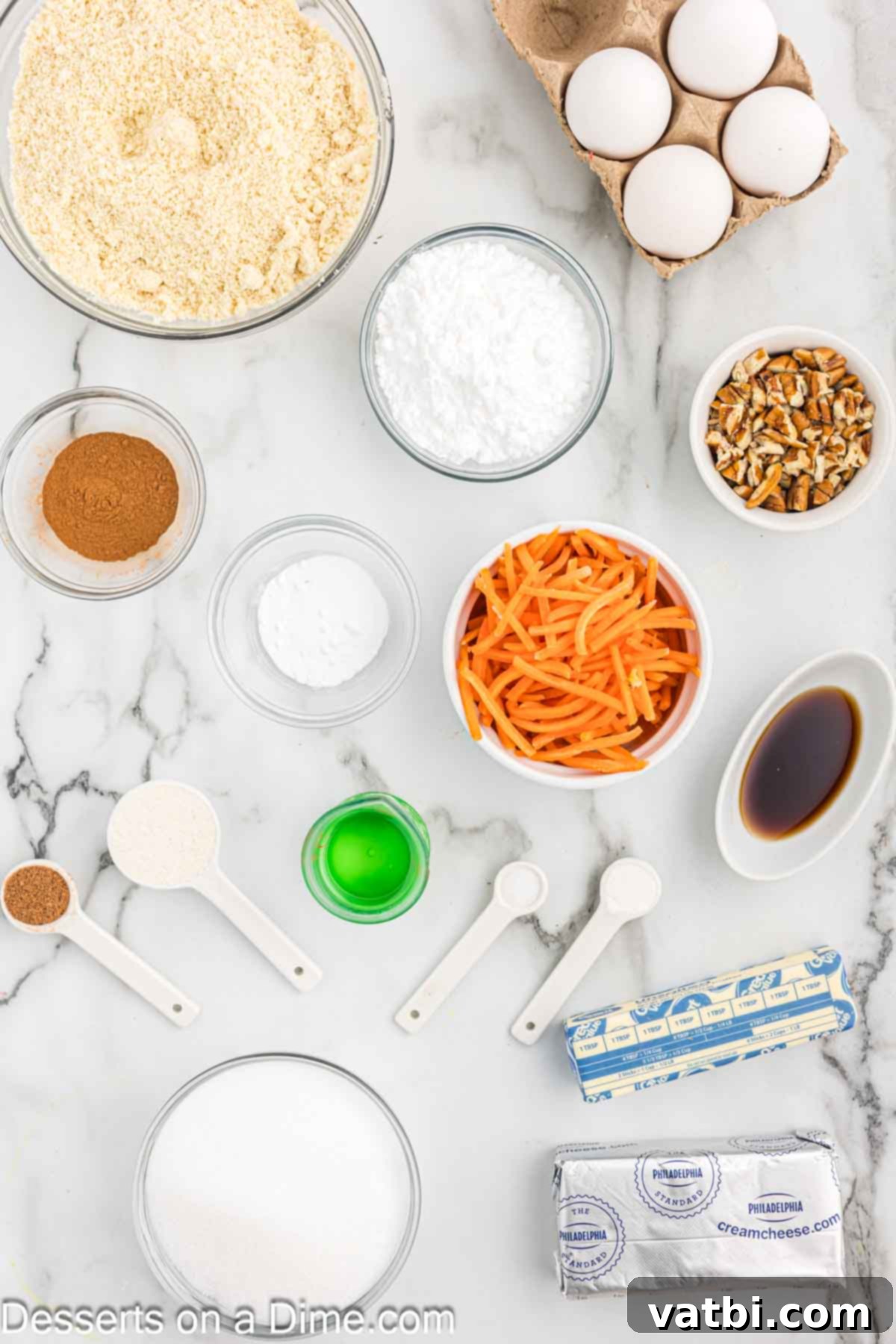 A flat lay photograph showcasing all the ingredients required for a Keto Carrot Cake, including eggs, coconut oil, vanilla extract, monk fruit sweetener, almond flour, coconut flour, baking soda, baking powder, nutmeg, cinnamon, salt, butter, chopped pecans, and freshly shredded carrots.