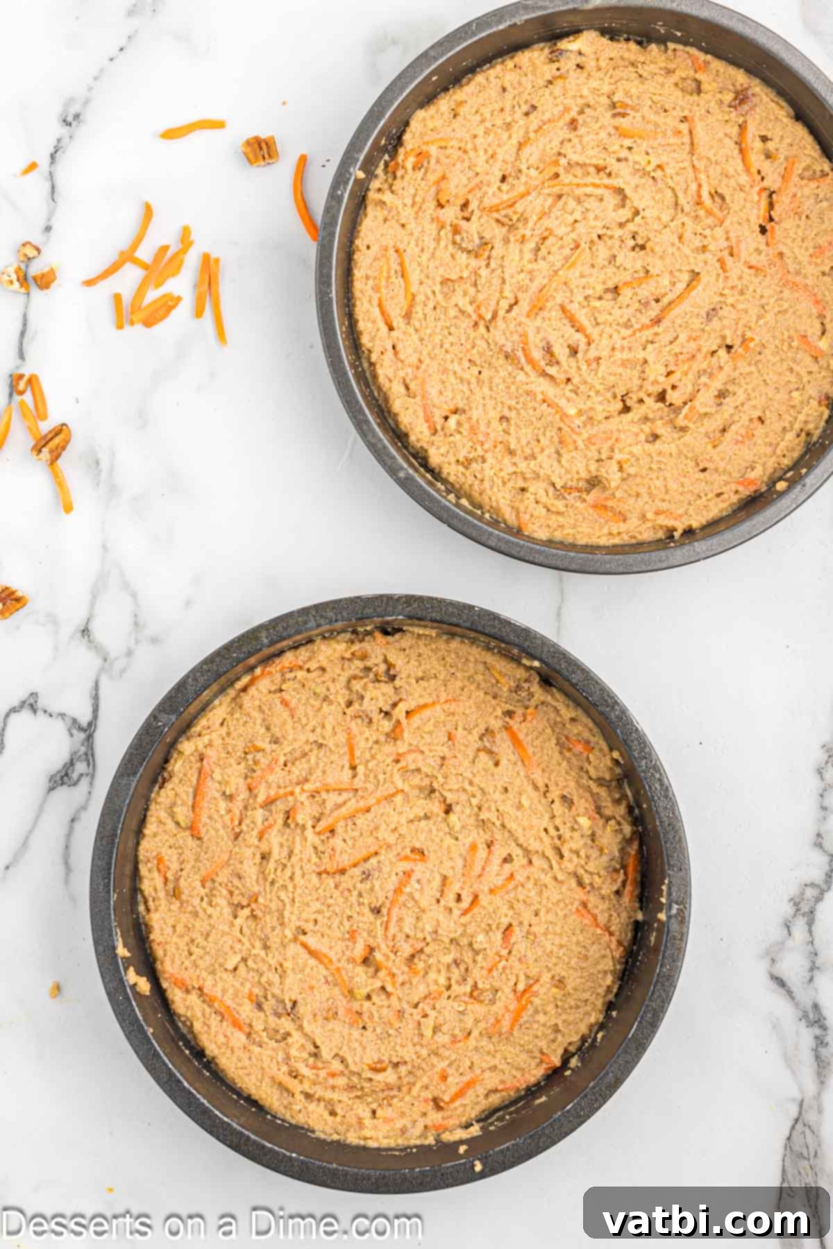 Cake batter evenly poured into two round cake pans, ready for baking.