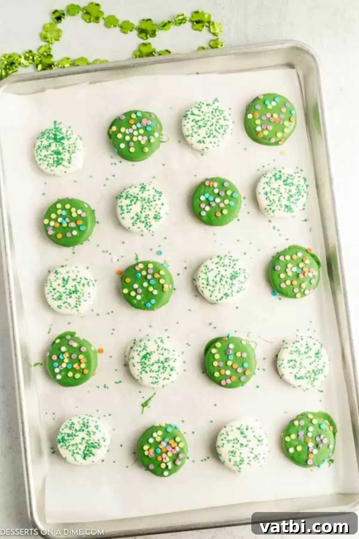 St Patricks Day Oreo Chocolate Delights 5 Freshly dipped chocolate covered Oreos adorned with festive green and rainbow sprinkles on a baking sheet.