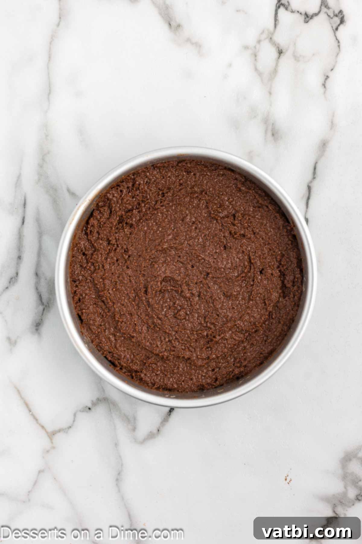 Decadent Keto Chocolate Delight 6 Smooth chocolate cake batter evenly spread in a round cake pan, ready to be placed in the oven for baking, highlighting the meticulous preparation.
