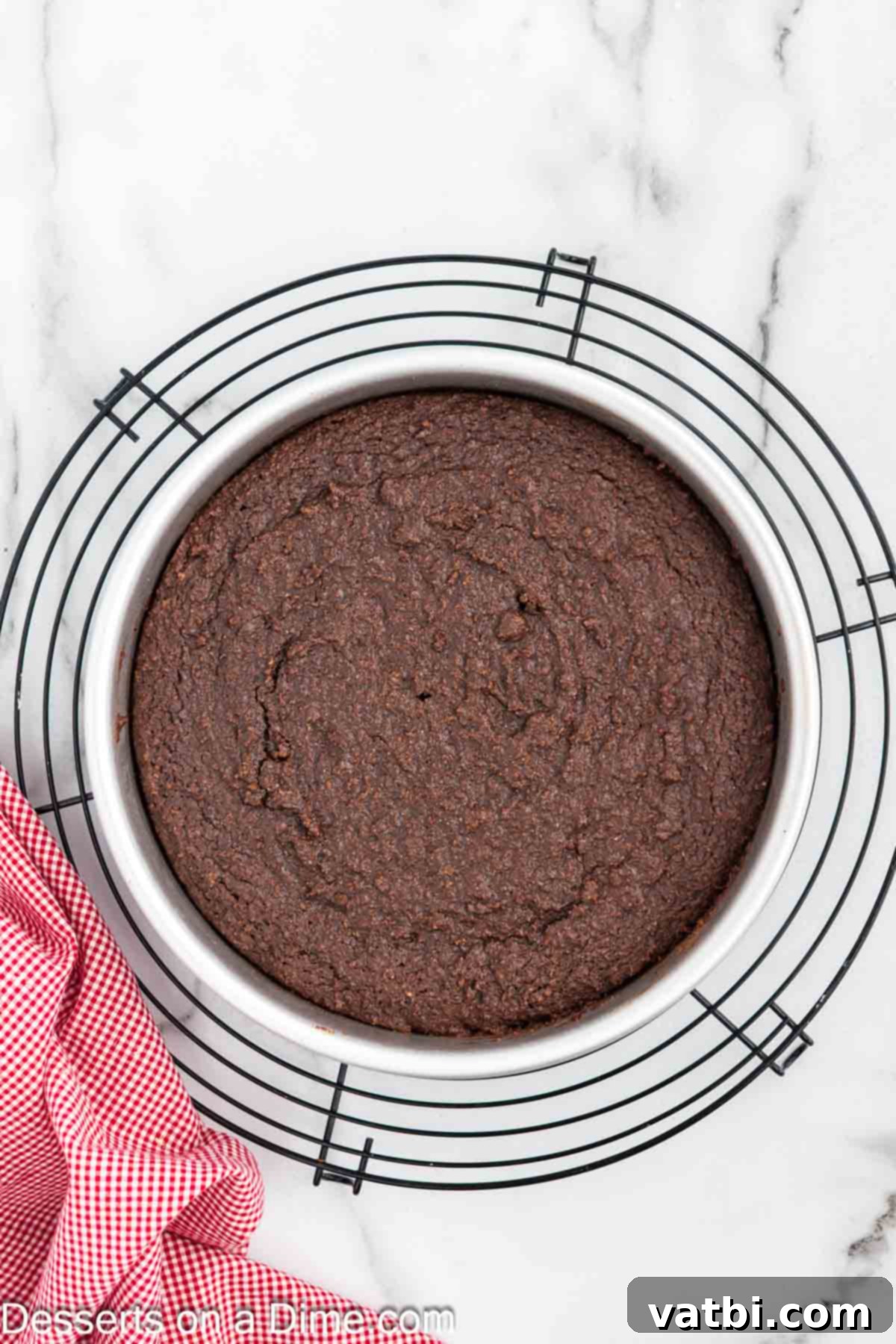 Decadent Keto Chocolate Delight 7 A freshly baked keto chocolate cake, golden-brown and perfectly risen, cooling on a wire rack to ensure even temperature distribution and prevent sogginess.