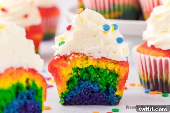 Spectrum Sweets 2 Rainbow Cupcakes cut in half, revealing colorful layers.