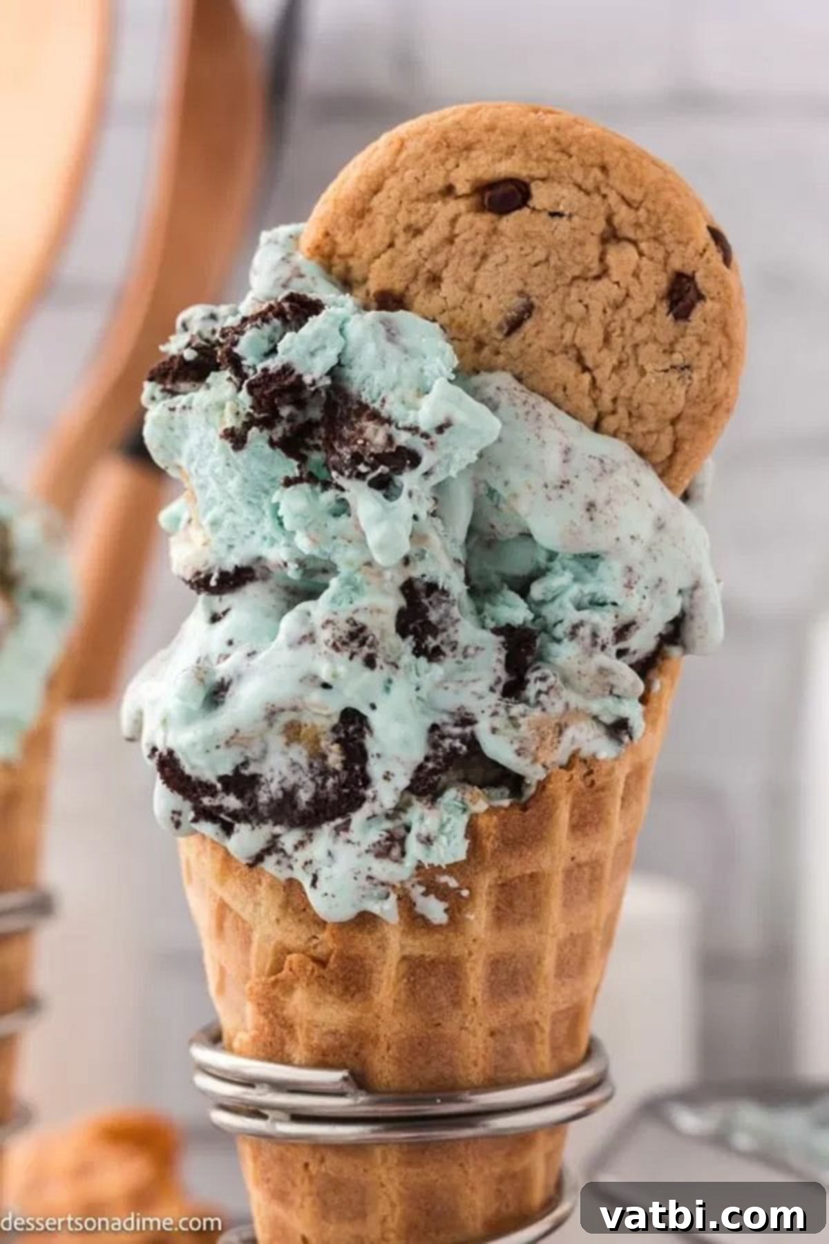 A vibrant blue scoop of Cookie Monster ice cream, studded with cookie pieces, served in a crisp sugar cone.