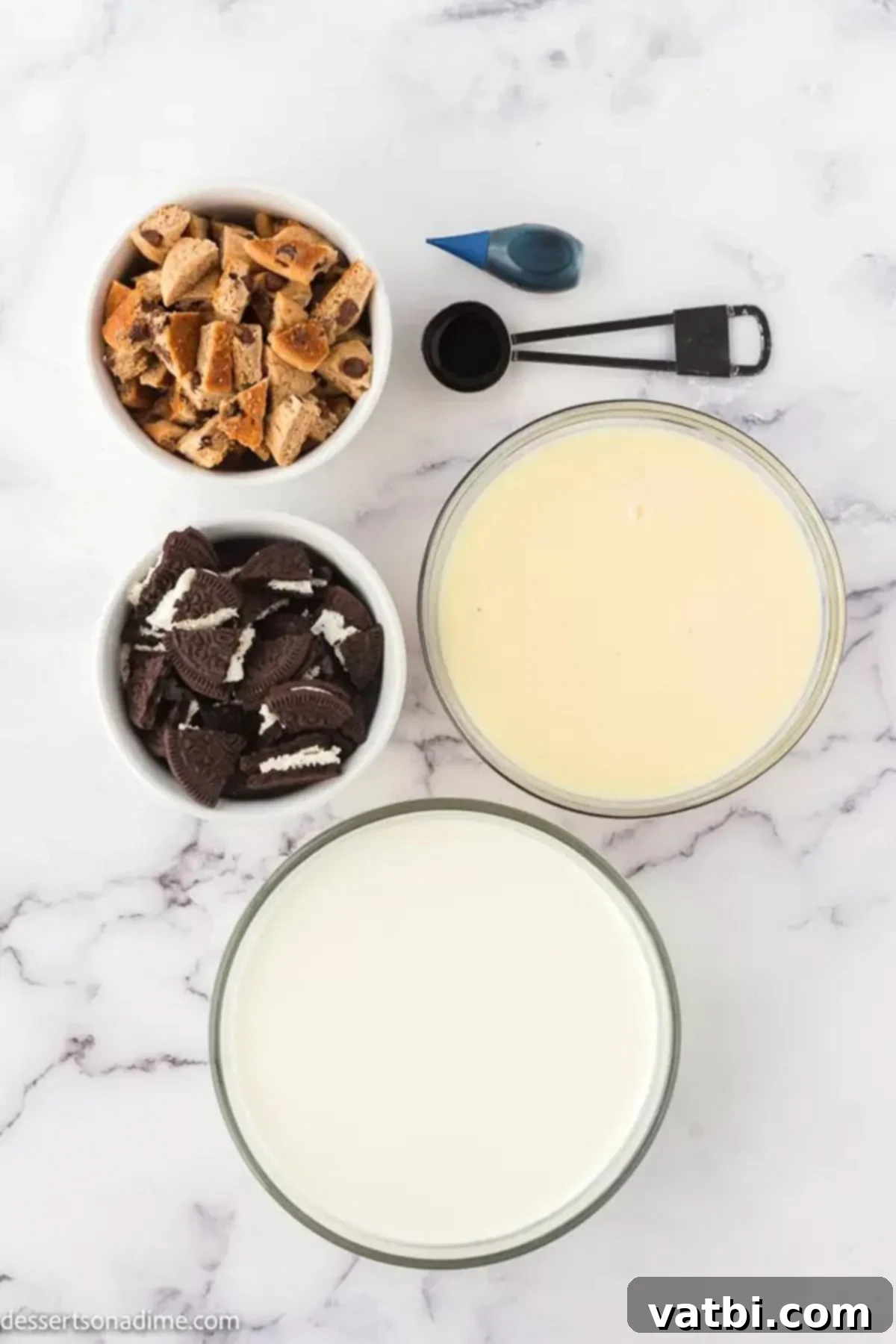 A flat lay image displaying the key ingredients for Cookie Monster ice cream: heavy whipping cream, vanilla extract, sweetened condensed milk, chopped Oreos, and chocolate chip cookies.