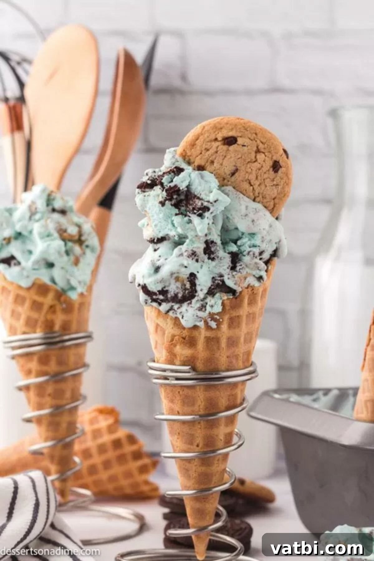 Scoops of Cookie Monster ice cream, garnished with cookie pieces, served in waffle cones for enjoyment.