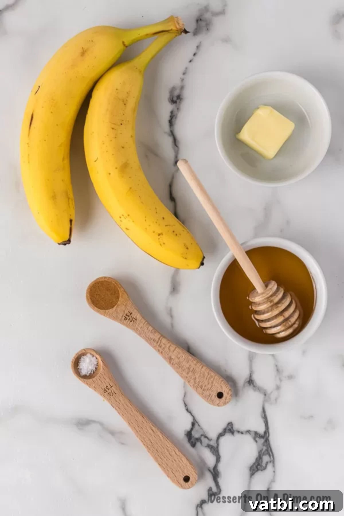Sweet Golden Banana Bites 3 Ingredients for fried bananas laid out: fresh bananas, a stick of butter, a jar of honey, and a bowl of cinnamon.