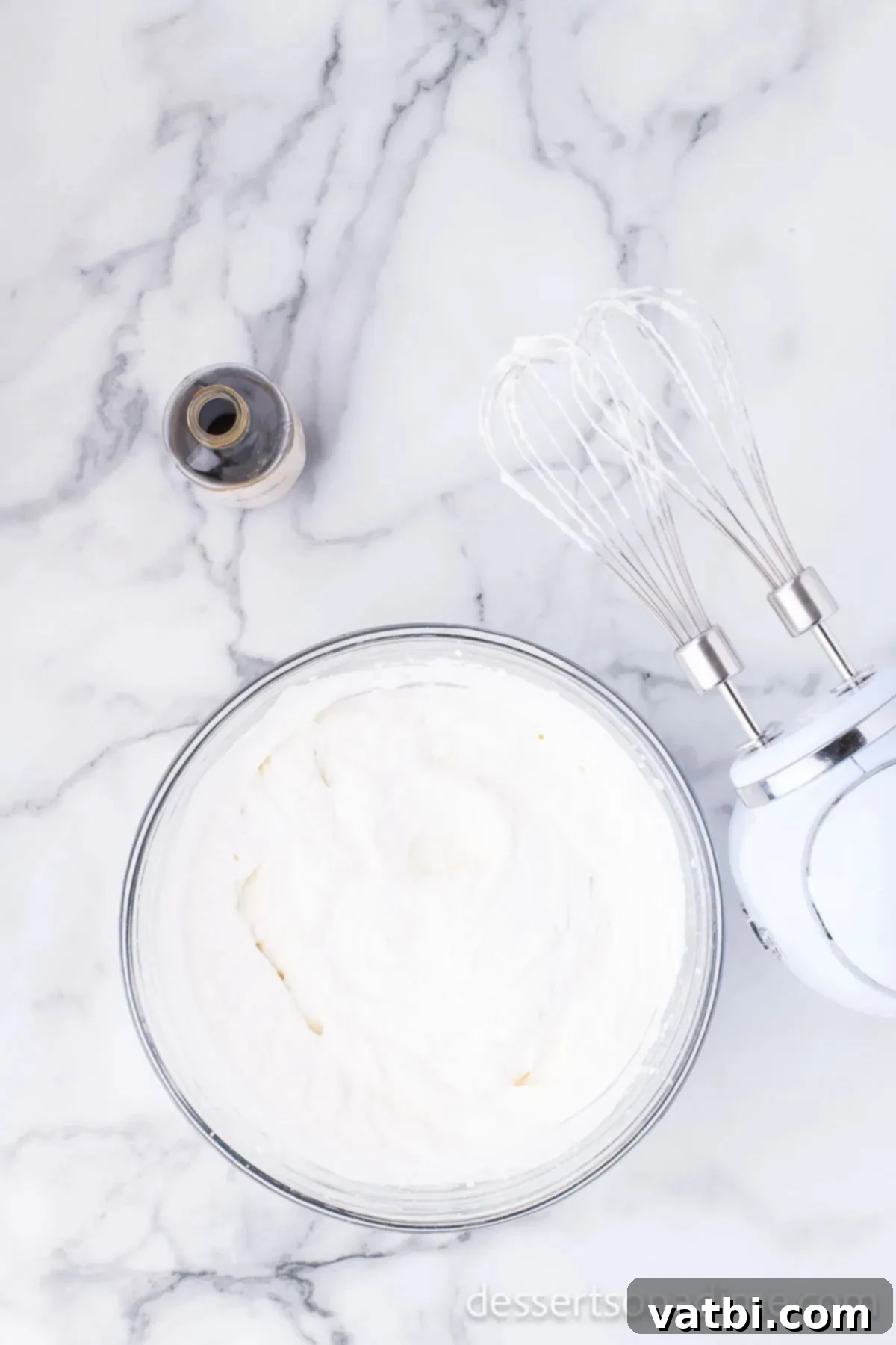 Primate's Perfect Scoop 4 A mixing bowl with heavy cream being whipped by a stand mixer.