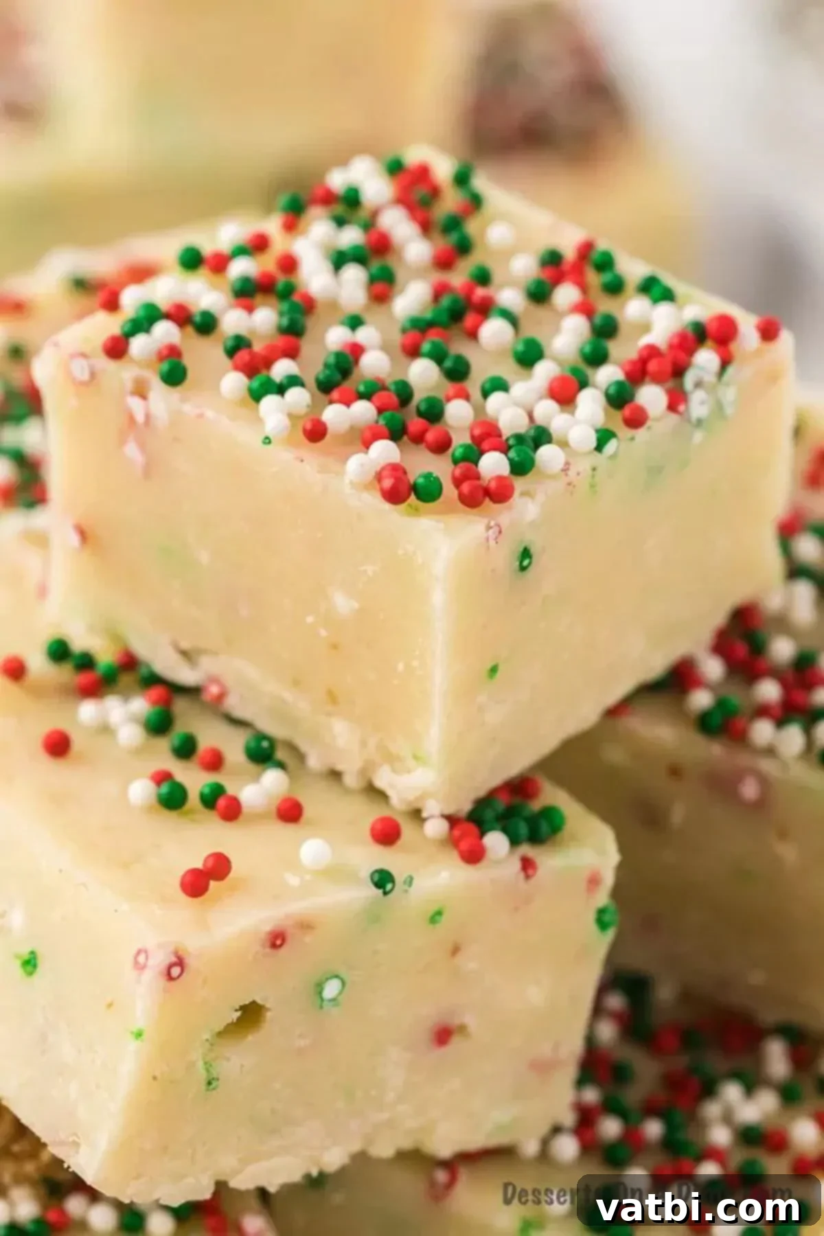 Ultimate Sugar Cookie Fudge 2 Sugar cookie fudge cut into bars, garnished with festive sprinkles on a white surface.