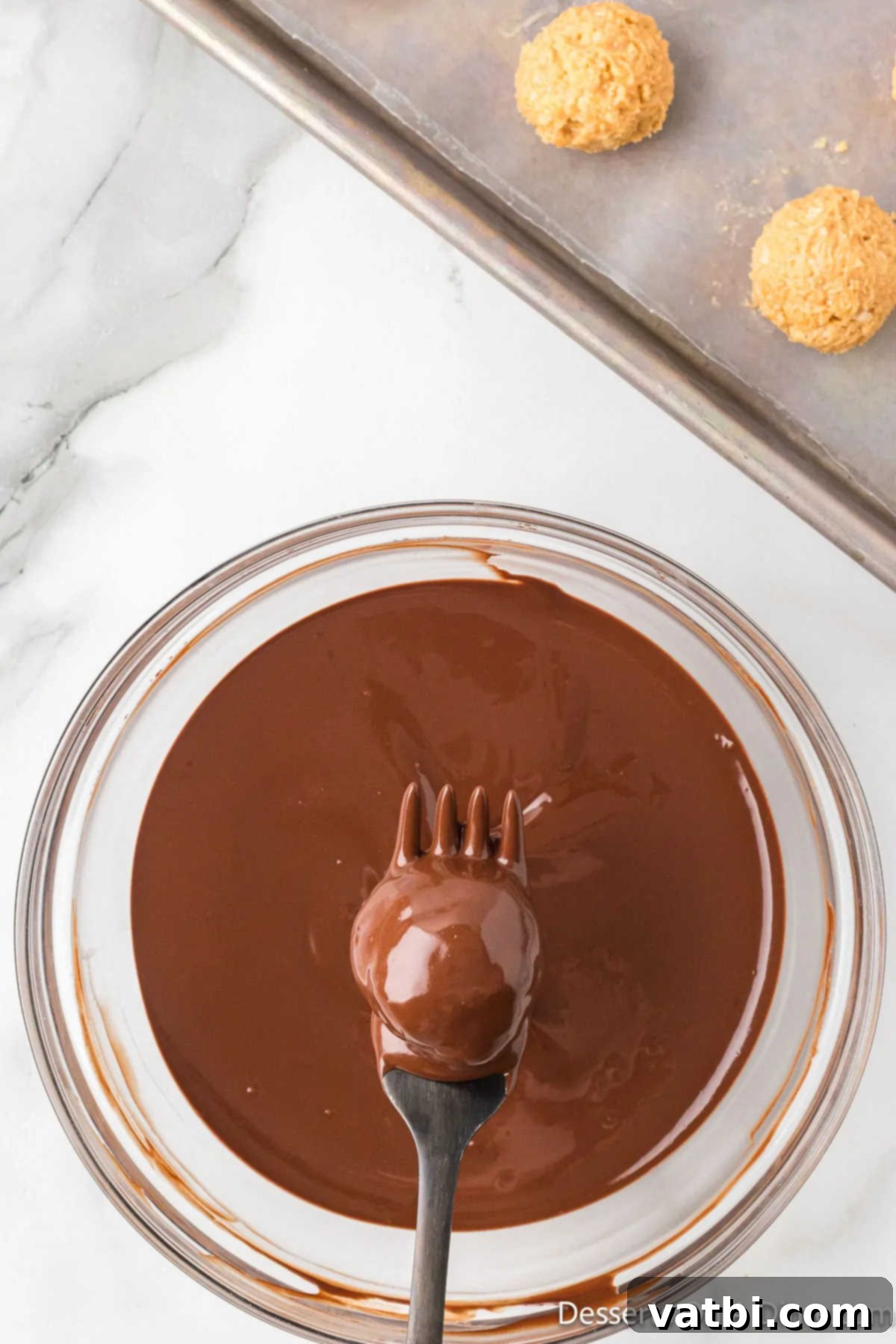 Peanut Butter Crisp Bites 13 Fork holding dough ball coated in chocolate.