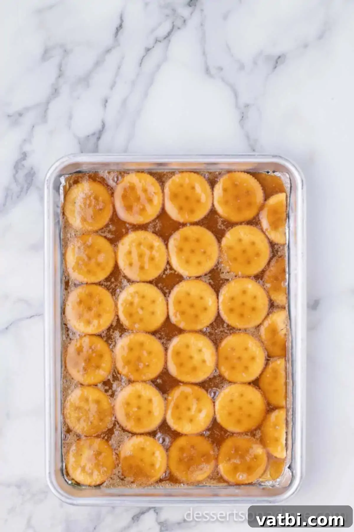 Sweet & Salty Ritz Toffee Bites 8 Mixture over pan of crackers.