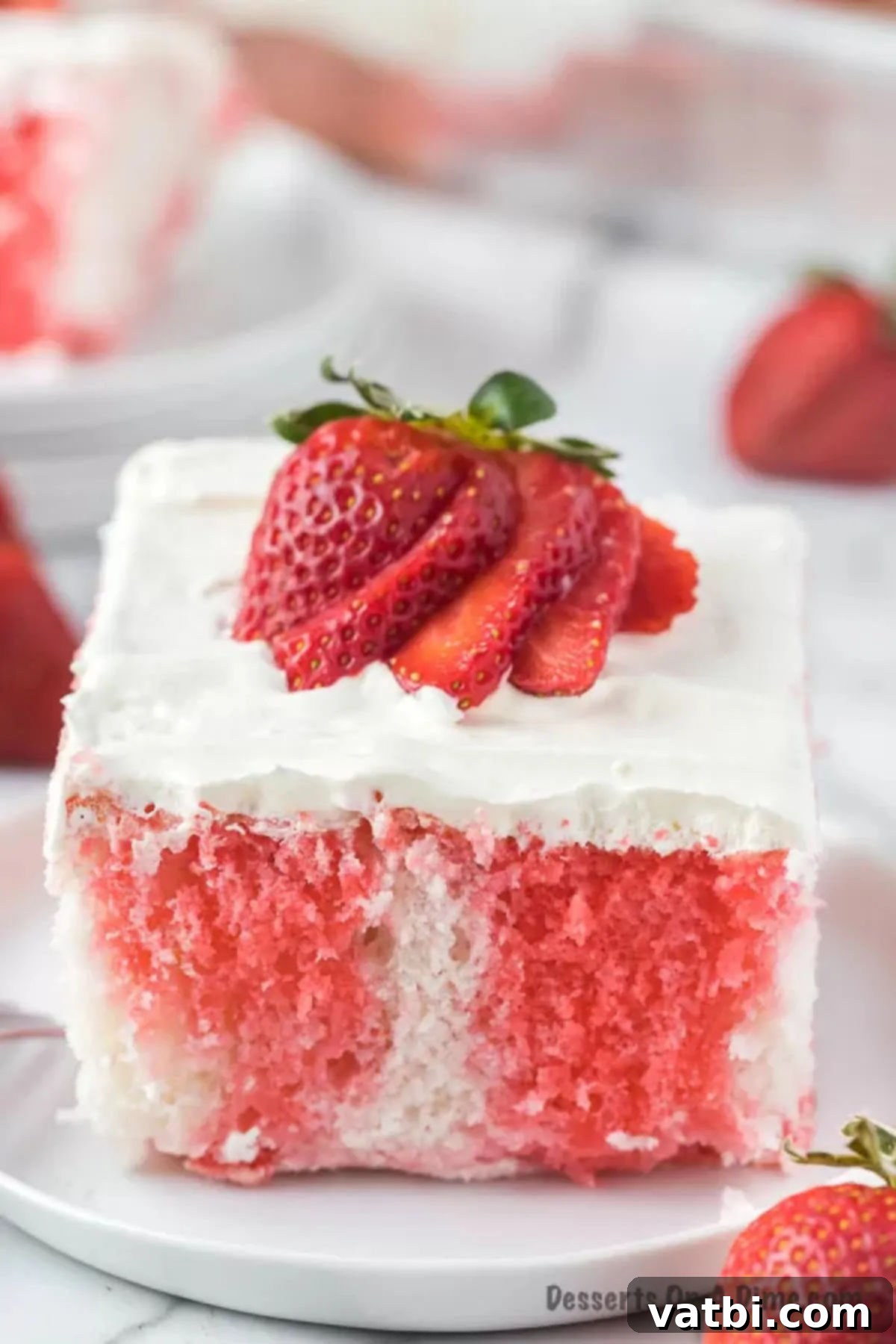 Strawberry Poke Cake sliced on a plate, revealing its moist, jello-infused layers and whipped topping.