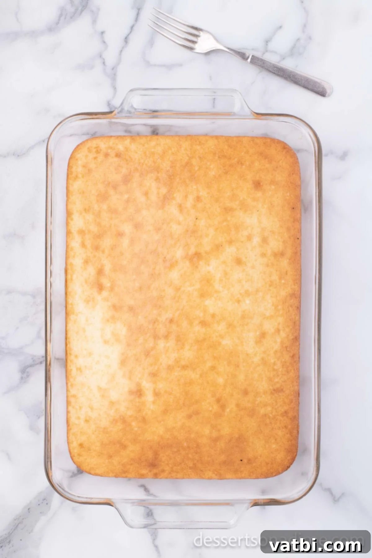 Baked white cake cooling in a 9x13 baking dish.