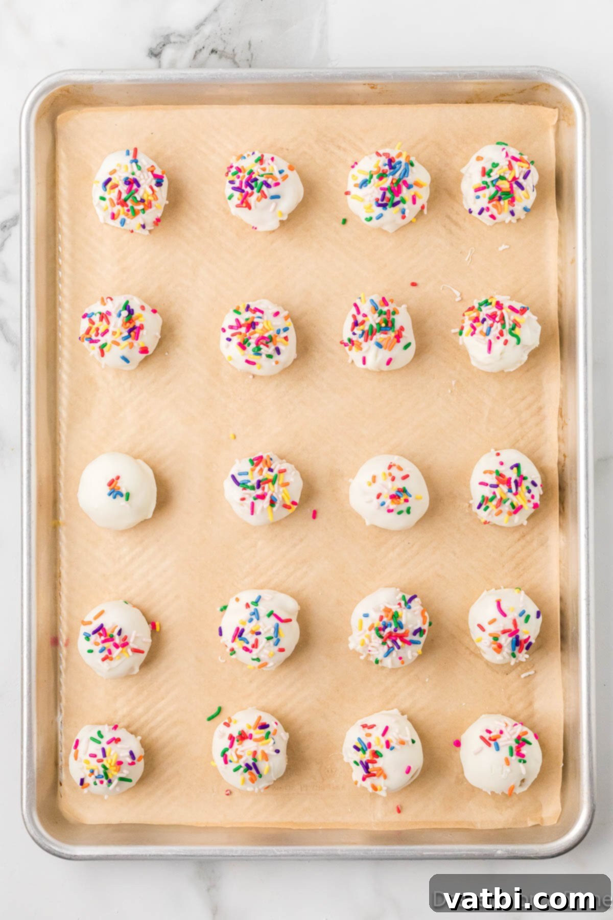 Homemade Vanilla Cake Delights 9 Finished vanilla cake balls arranged on a baking sheet lined with parchment paper.