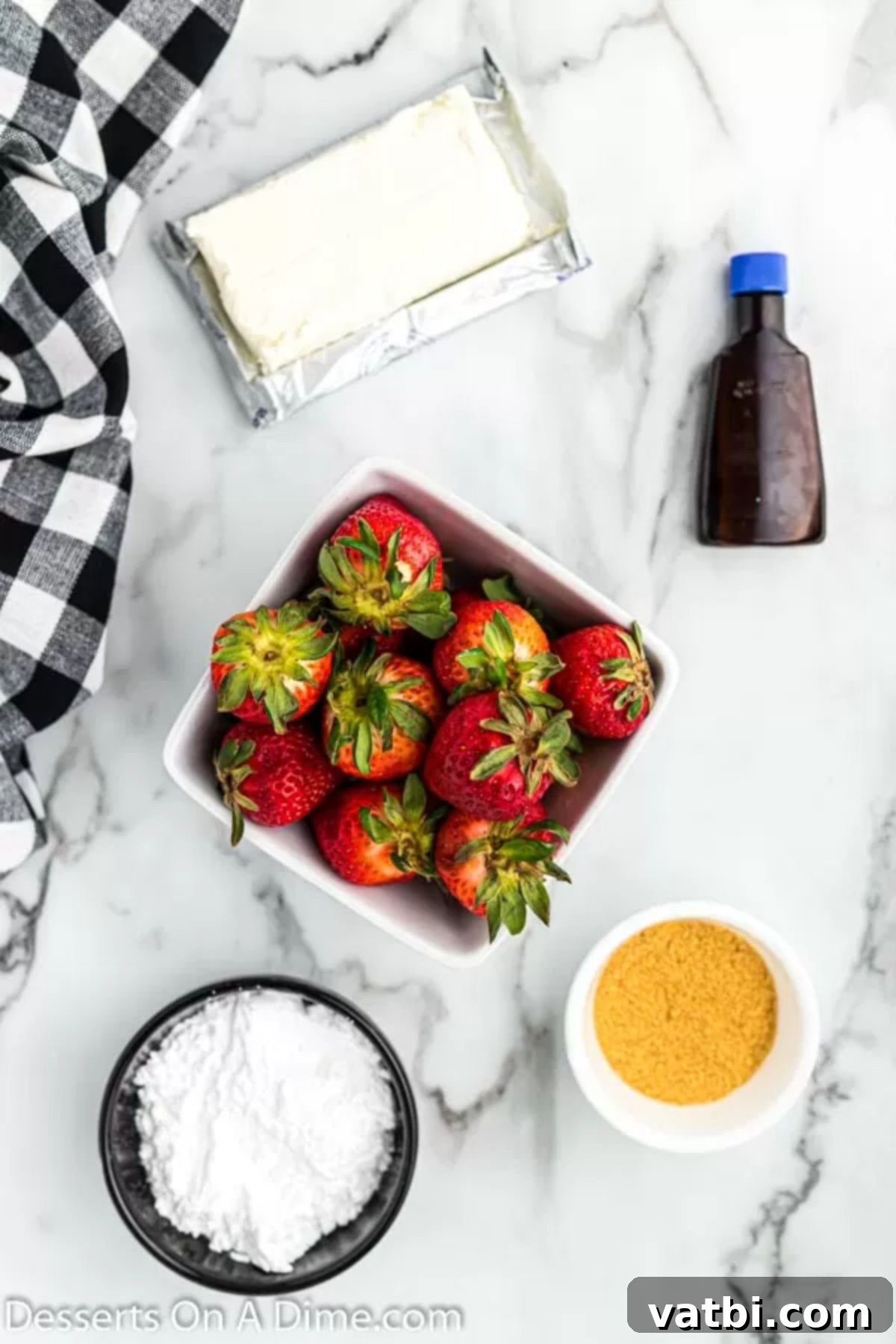 Decadent Cheesecake Filled Strawberries 3 Ingredients for recipe - strawberries, cream cheese, powdered sugar, vanilla, graham cracker crumbs laid out on a surface.