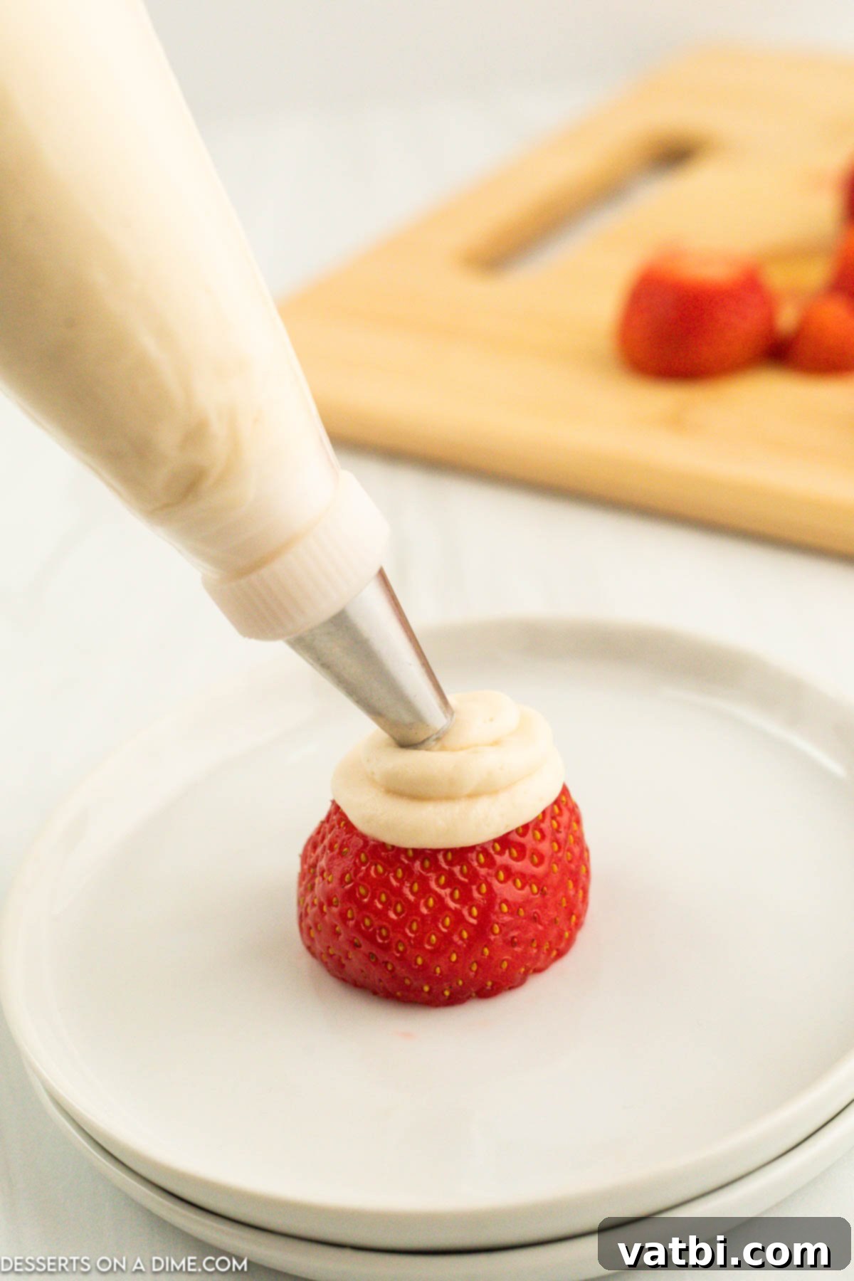 Mixture in piping bag on strawberry. 