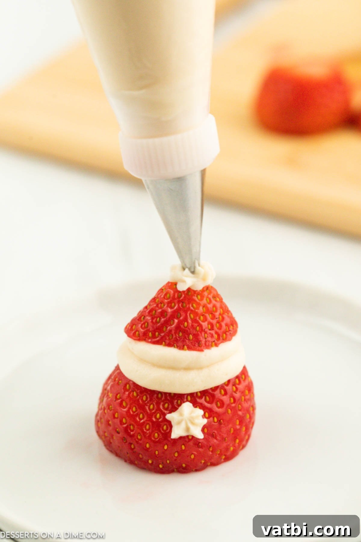 Strawberries being garnished with filling on top. 
