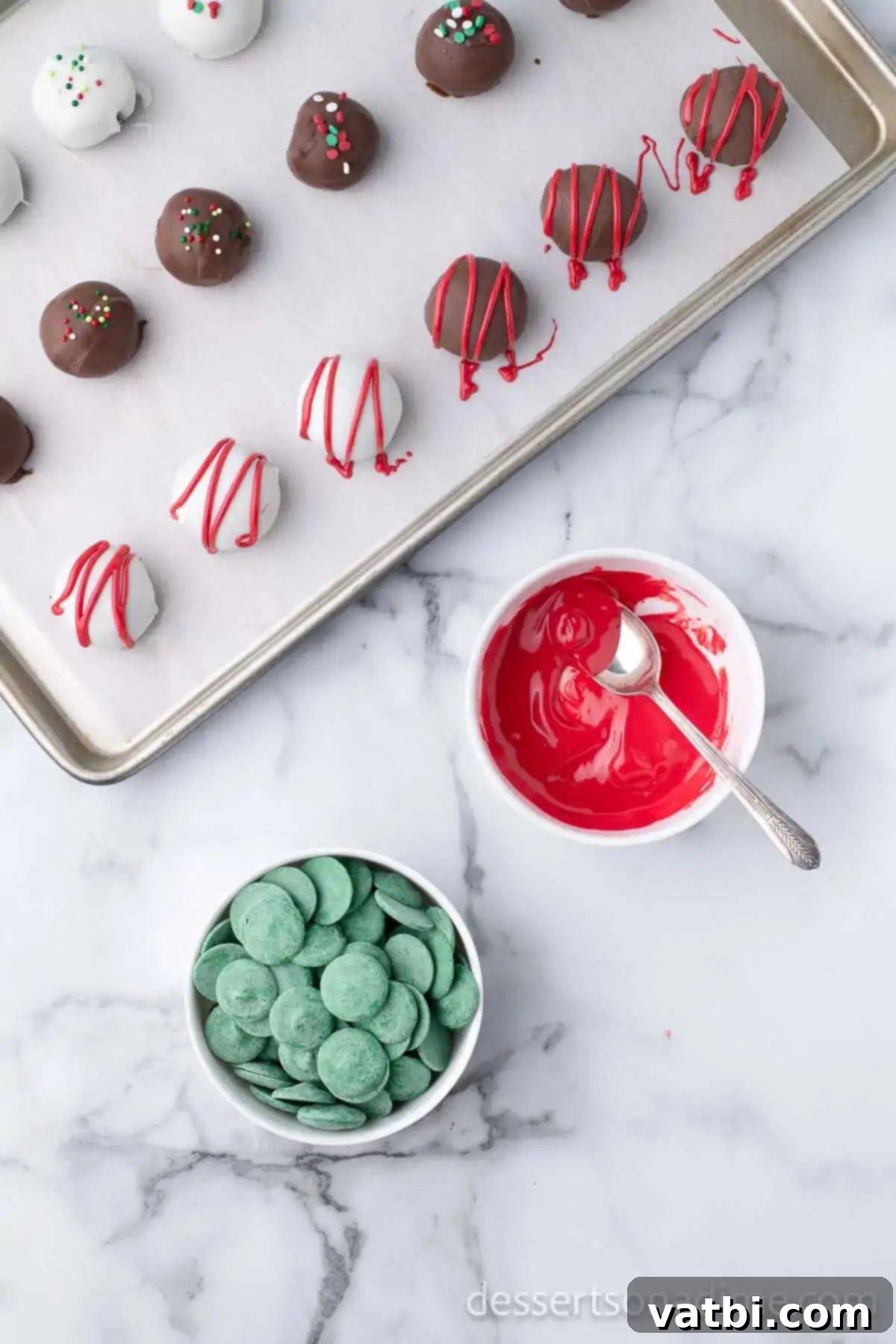 Easy Christmas Oreo Balls 11 Melted green candy melts being drizzled over chocolate-coated Oreo truffles.