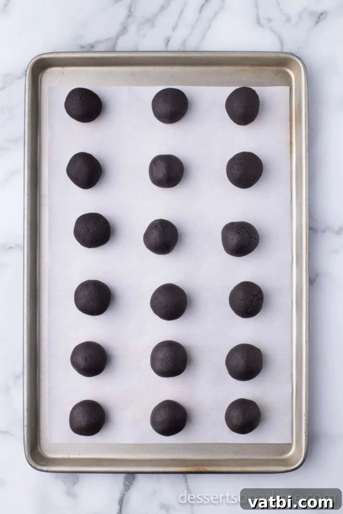 Easy Christmas Oreo Balls 7 Rolled Oreo balls placed on a baking sheet lined with parchment paper, ready for freezing.