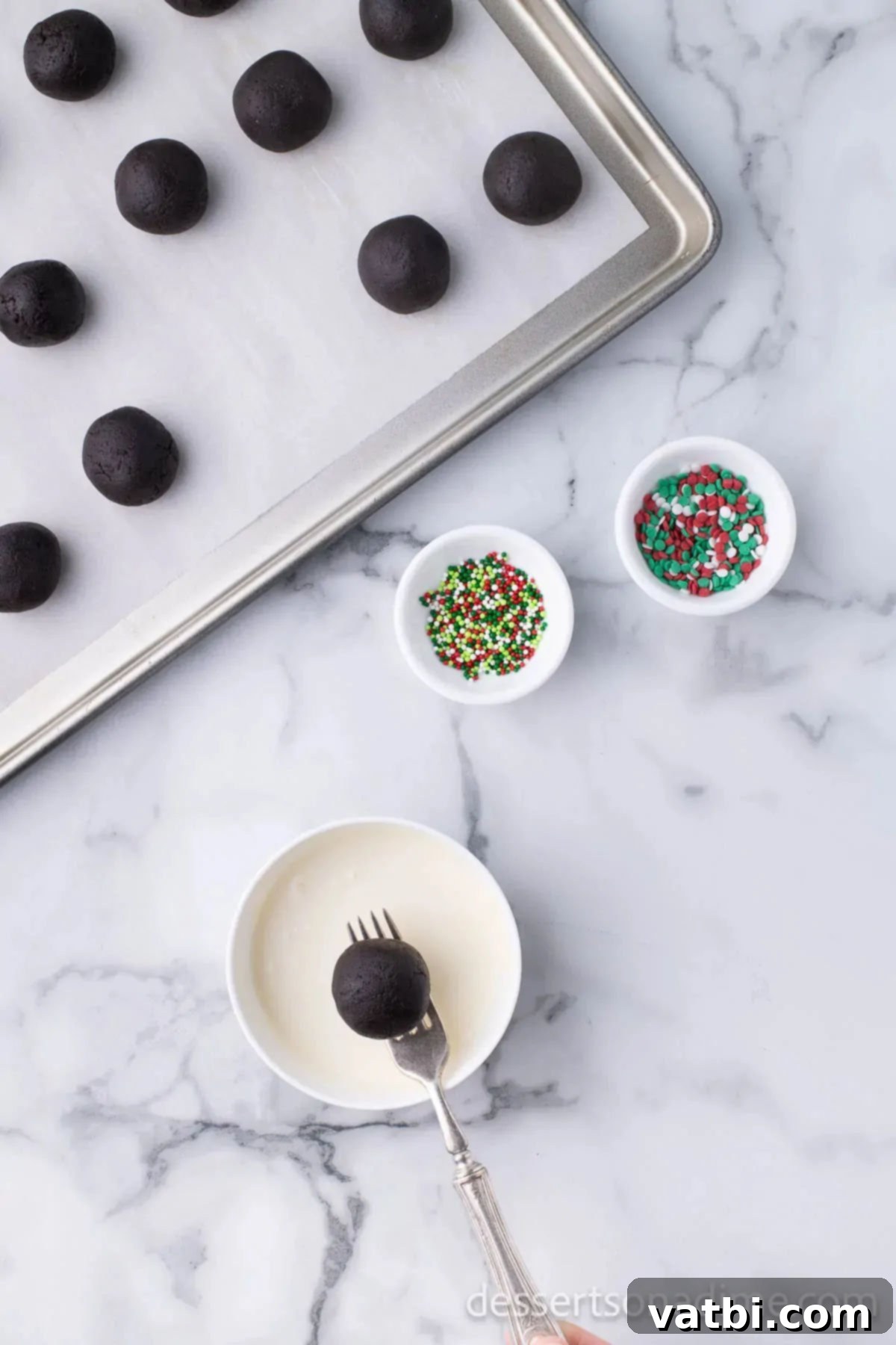 Easy Christmas Oreo Balls 9 Oreo balls being dipped into melted chocolate with a fork.