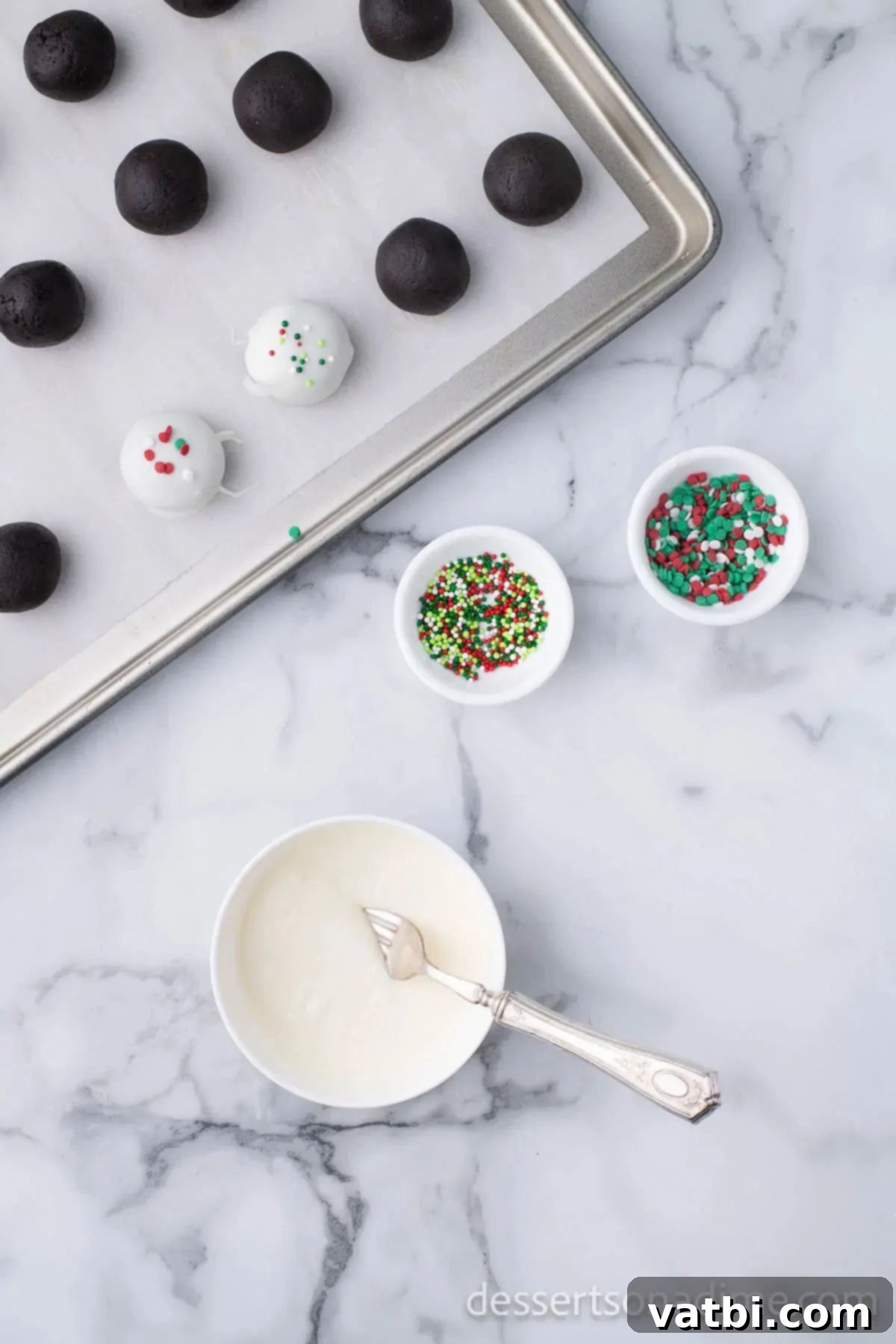 Easy Christmas Oreo Balls 10 Chocolate-dipped Oreo truffles being topped with festive Christmas sprinkles.