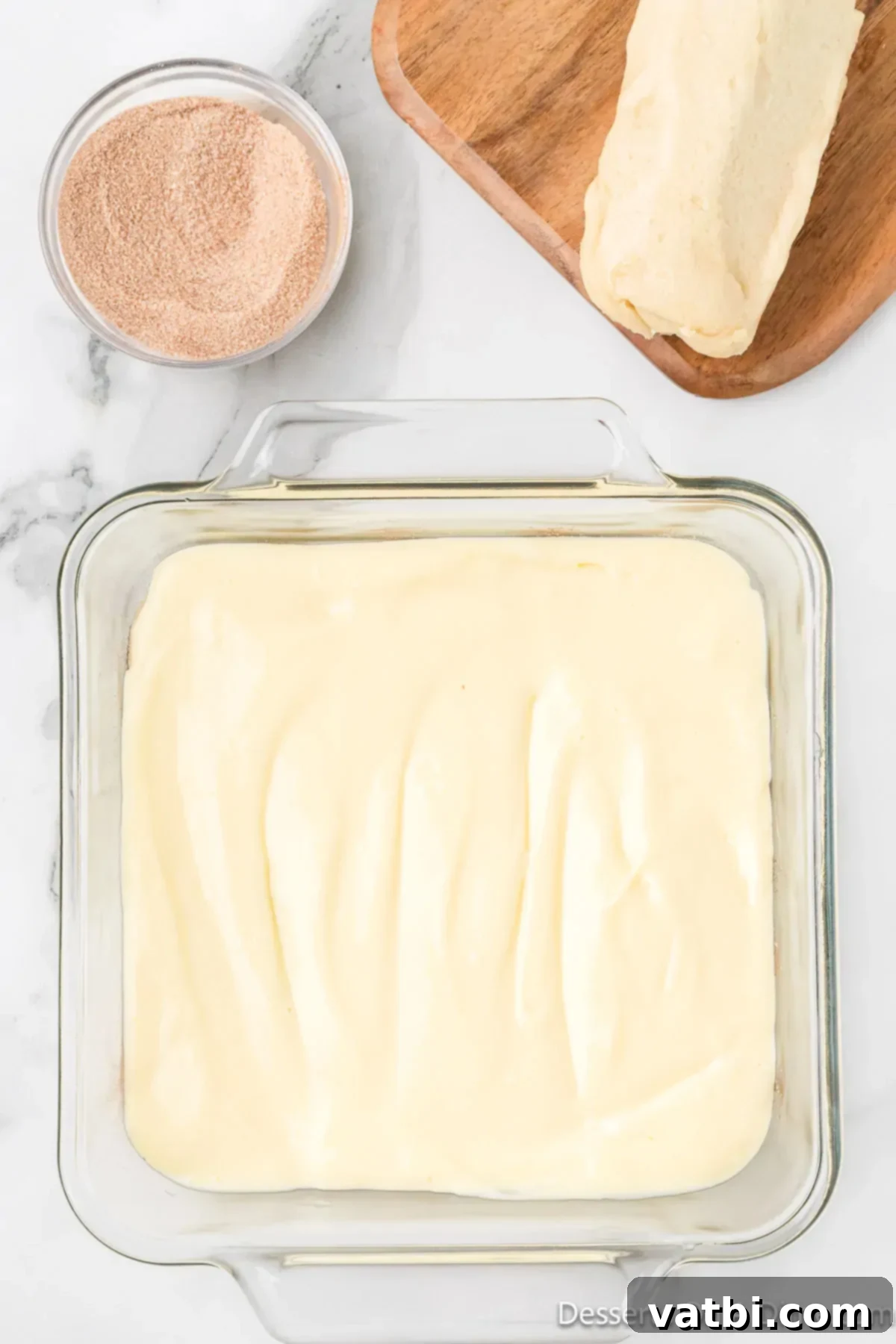 Dreamy Snickerdoodle Cheesecake Bars 9 Cheesecake filling spread on top of dough. The creamy cheesecake filling is spread in an even layer over the cinnamon-sugar dusted cookie dough crust.