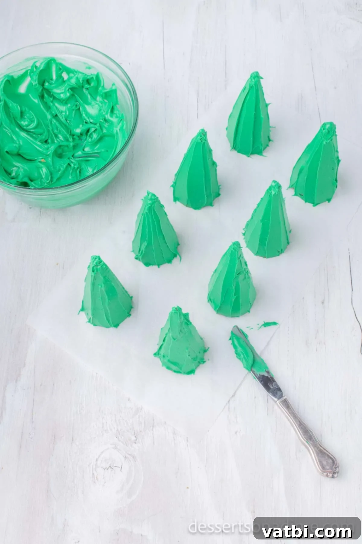 Sweet Ice Cream Cone Christmas Trees 6 Green frosting being applied onto an upside-down ice cream cone with a butter knife.