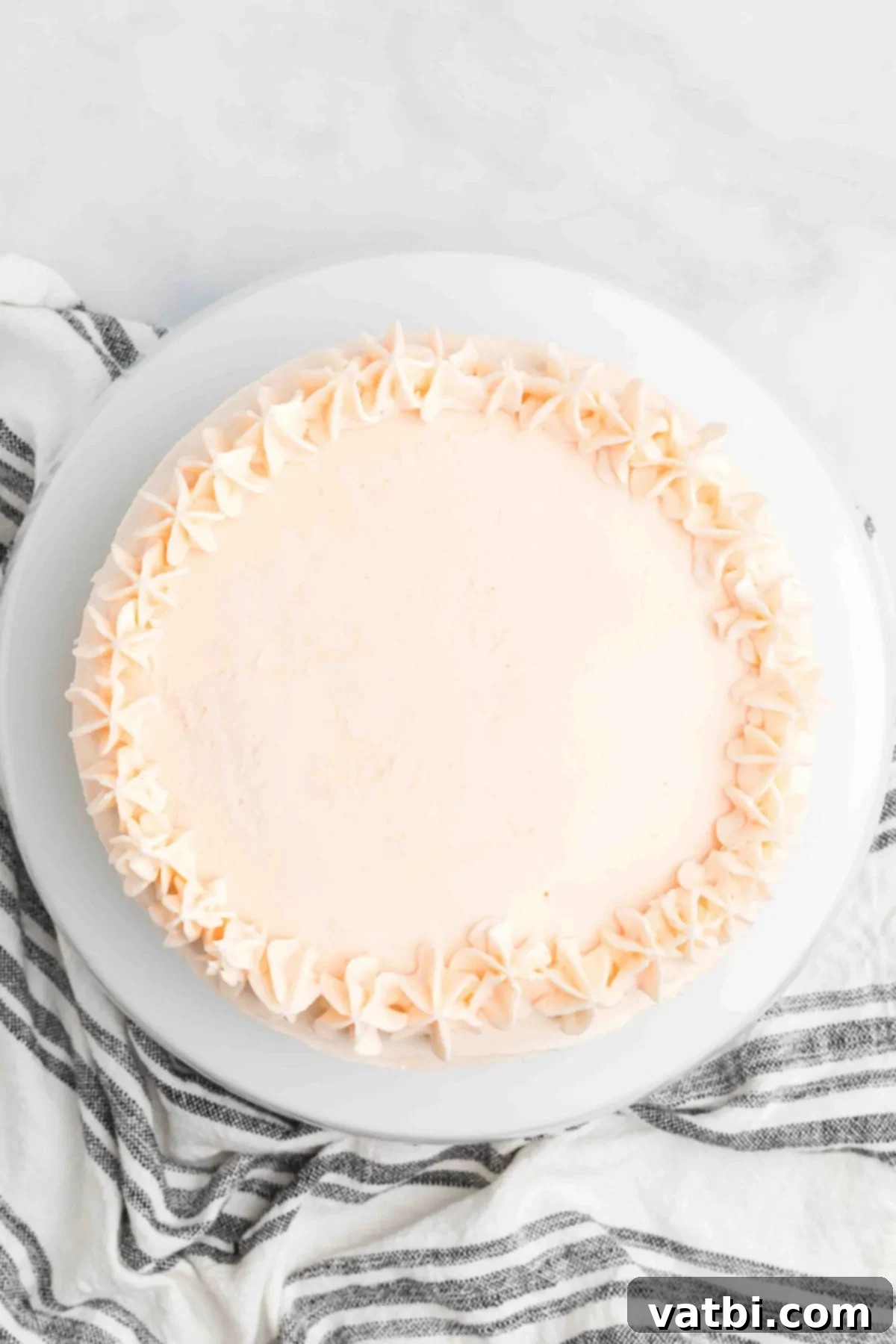 Perfect Cherry Chip Cake 13 Completely frosted cake with swirls of pink buttercream on top.