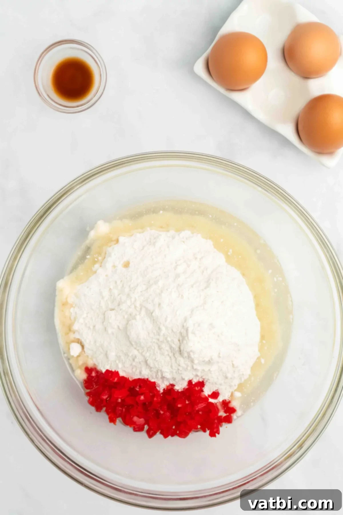 Perfect Cherry Chip Cake 6 Large mixing bowl with white cake mix, chopped cherries, eggs, and liquid ingredients ready to be mixed.