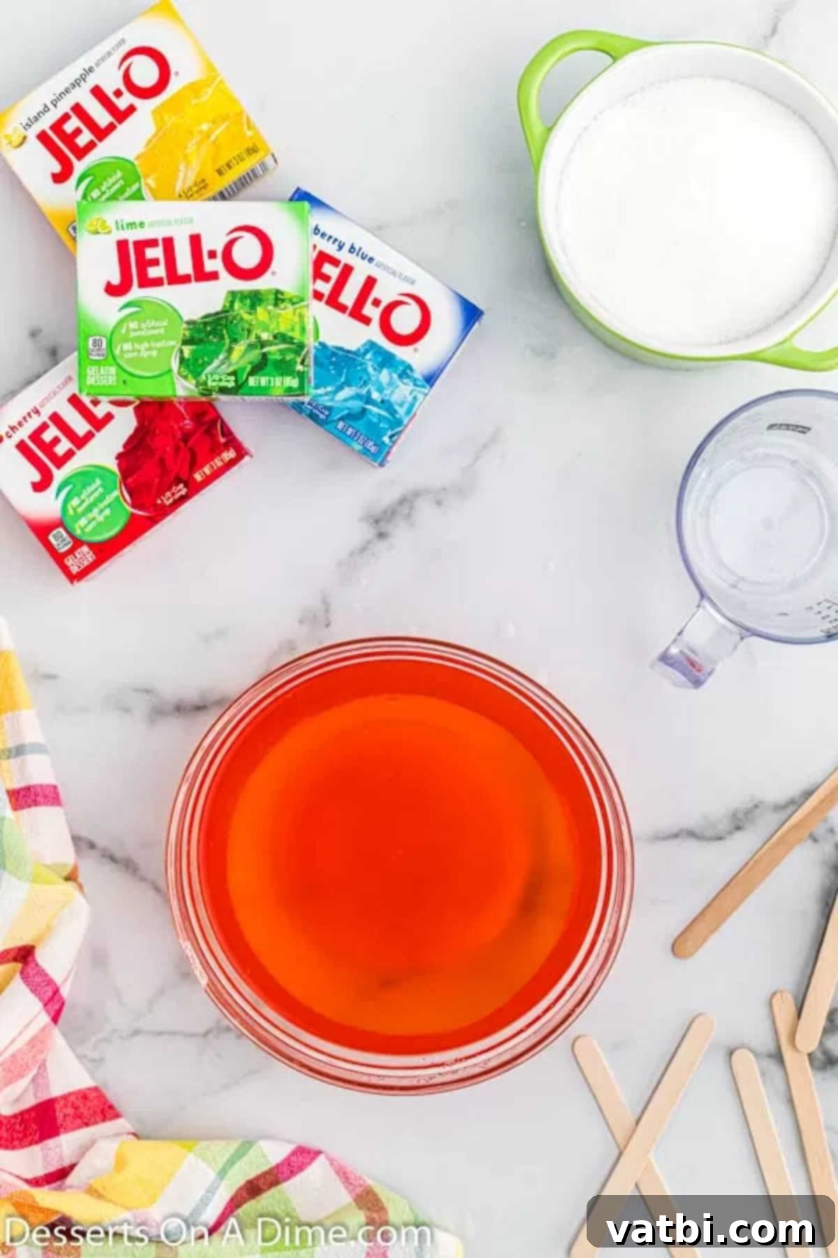 Easy Homemade Jello Pops 4 Jello powder and sugar dissolved perfectly in hot water, creating a vibrant liquid mixture in a bowl.