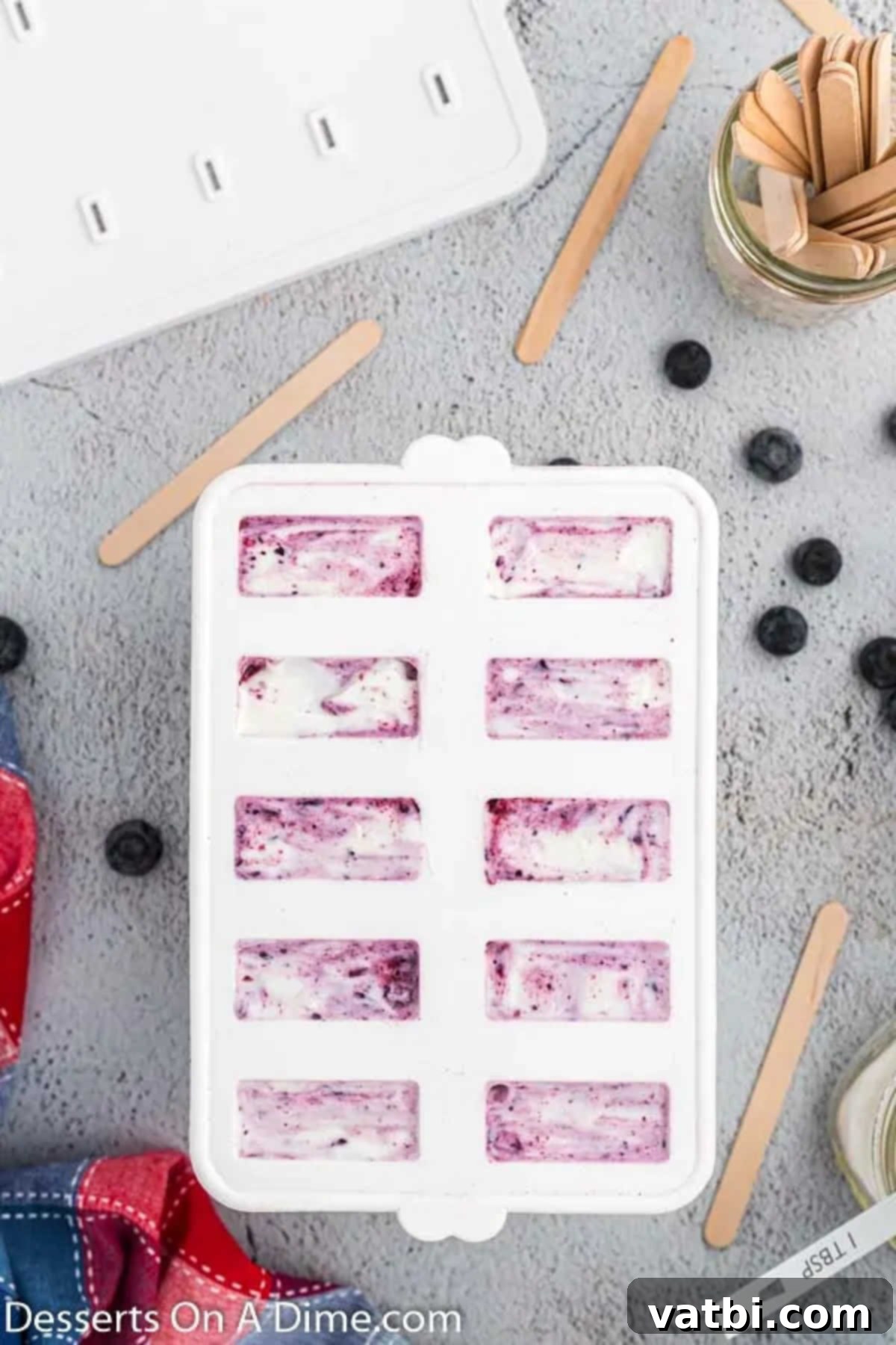 Blueberry Freeze Pops 6 The blueberry and yogurt swirl mixture being poured evenly into individual popsicle molds, ready for freezing.