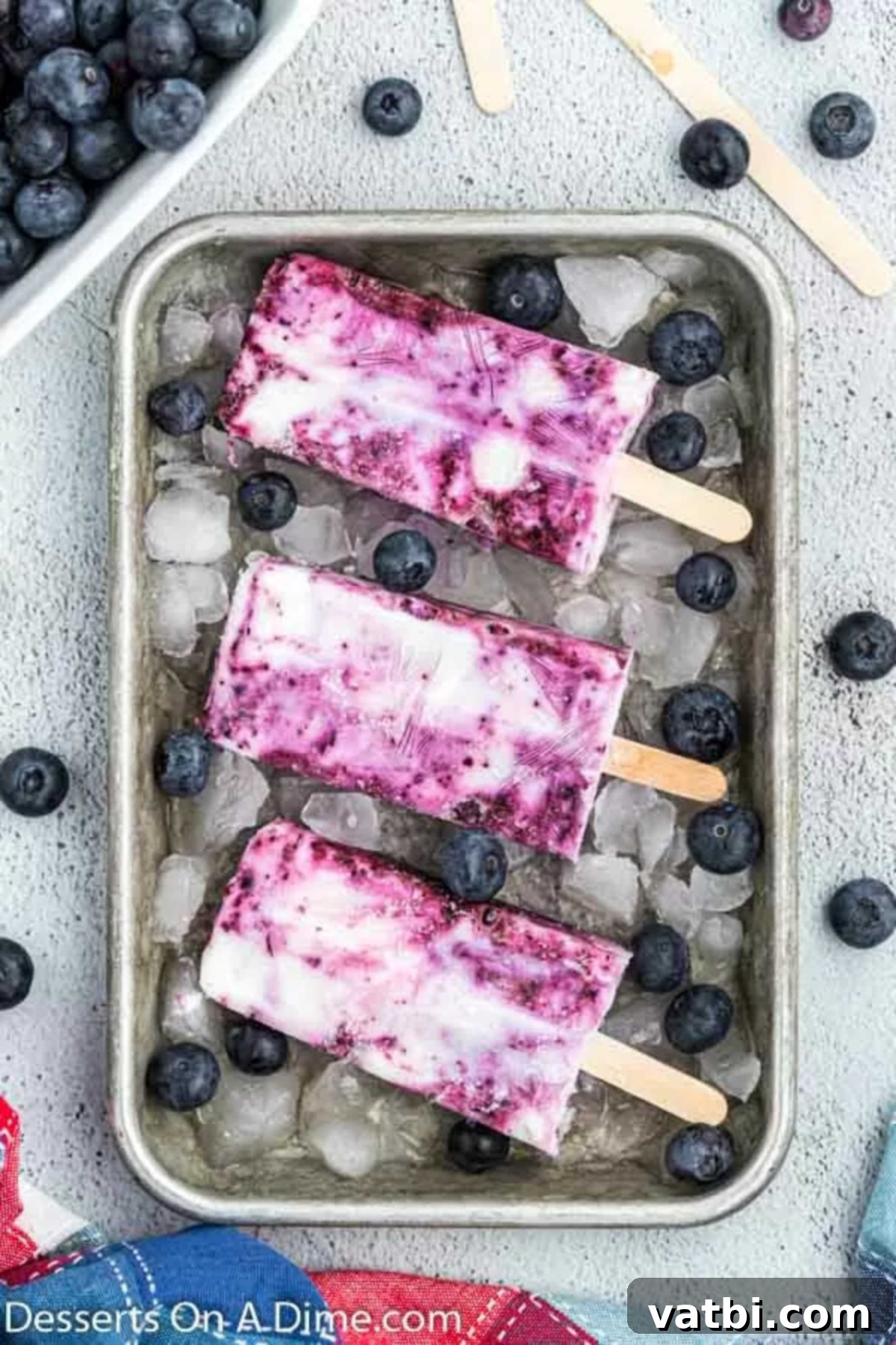 Blueberry Freeze Pops 7 Frozen blueberry popsicles, perfectly set in their molds, with wooden sticks, ready to be removed and enjoyed.