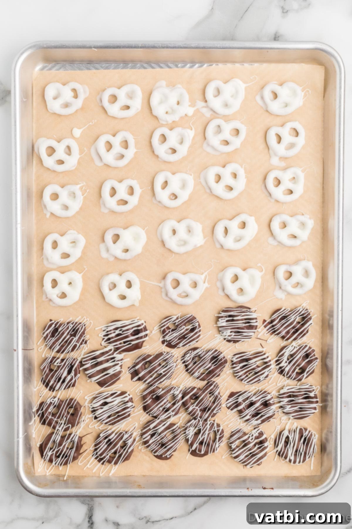 Sweet & Salty Pretzel Bliss 11 A full baking sheet showcasing a variety of chocolate-covered pretzels, some with contrasting drizzles and sprinkles, all waiting to fully set.