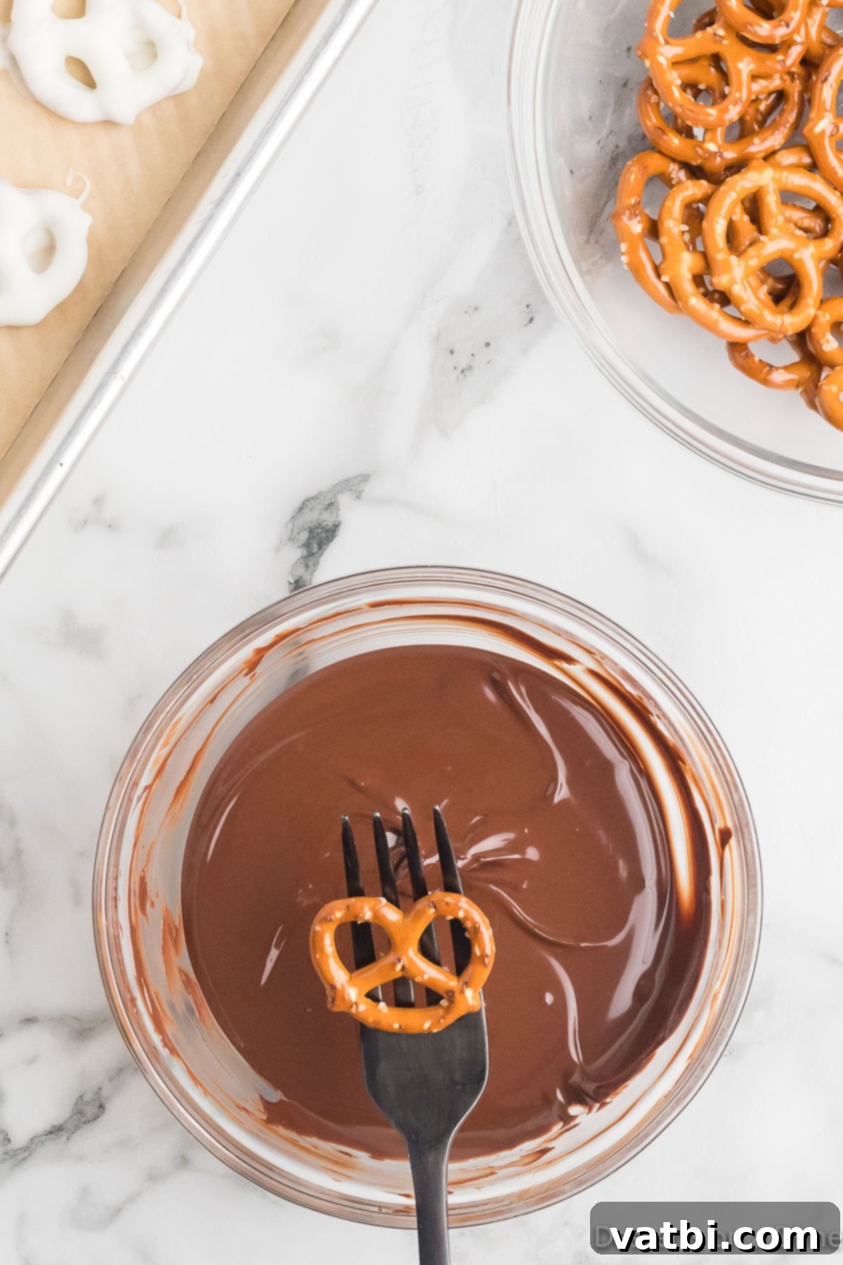 Sweet & Salty Pretzel Bliss 6 A pretzel held by a fork, ready to be dipped into a bowl of melted milk chocolate.