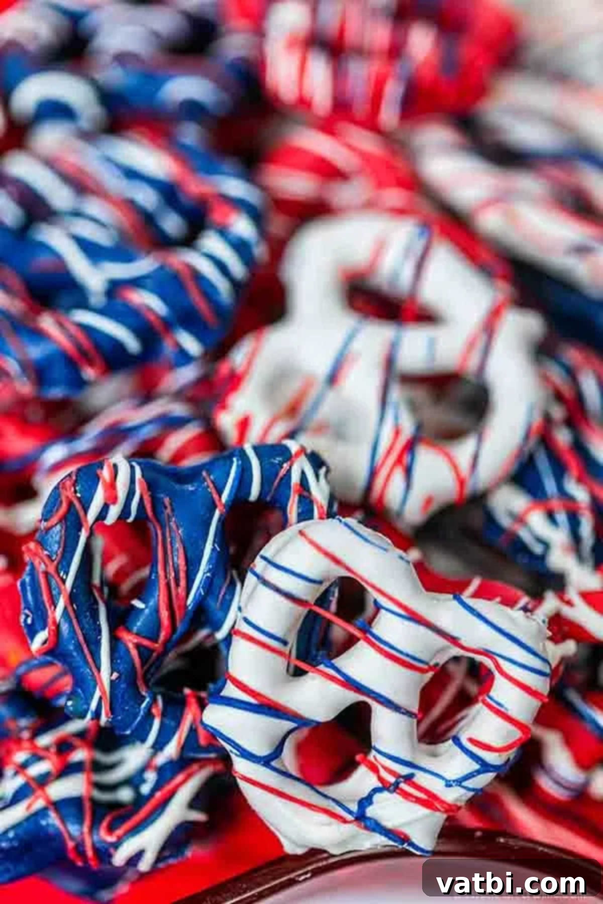 Celebrate the 4th of July with these festive and tasty Red white and blue chocolate covered pretzels. They are easy to make, inexpensive and so colorful. Red, White, and Blue Chocolate Covered Pretzels laid out on parchment paper