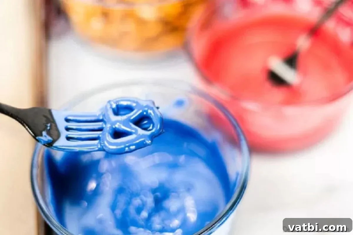 Red White and Blue Chocolate Dipped Pretzels 3 Pretzel being dipped into melted blue candy melts with a fork