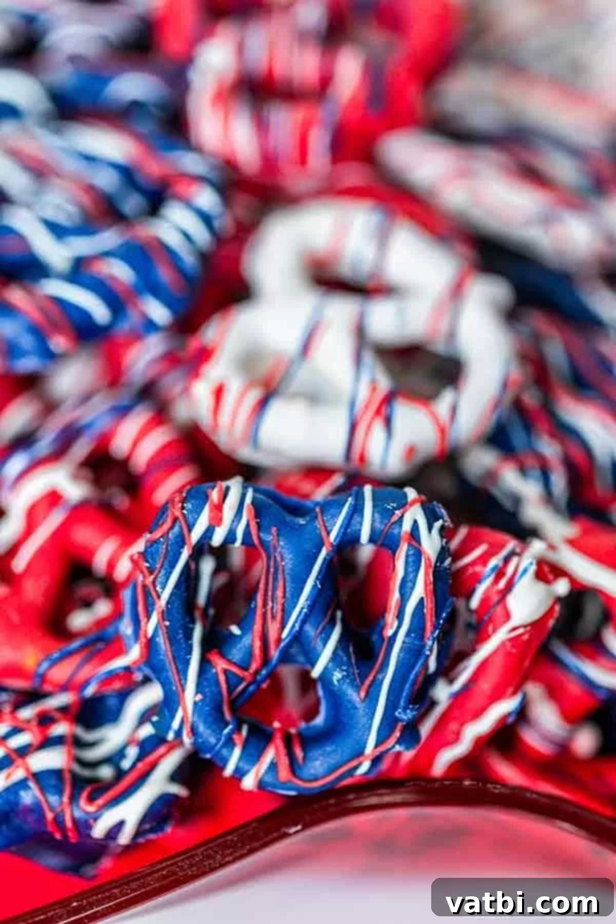 Celebrate the 4th of July with these festive and tasty Red white and blue chocolate covered pretzels. They are easy to make, inexpensive and so colorful. A close-up of a pile of finished Red, White, and Blue Chocolate Covered Pretzels