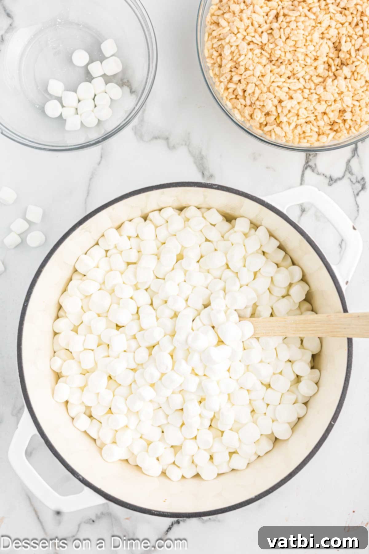 The Ultimate Rice Krispie Treat Recipe 5 Mini marshmallows being added to melted butter in a saucepan.