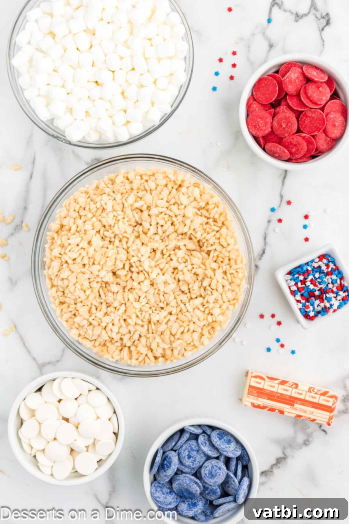 Patriotic Rice Krispie Delights 3 A flat lay of ingredients for Red, White and Blue Rice Krispie Treats: Rice Krispie cereal, butter, marshmallows, red, white, and blue candy melts, and star sprinkles.