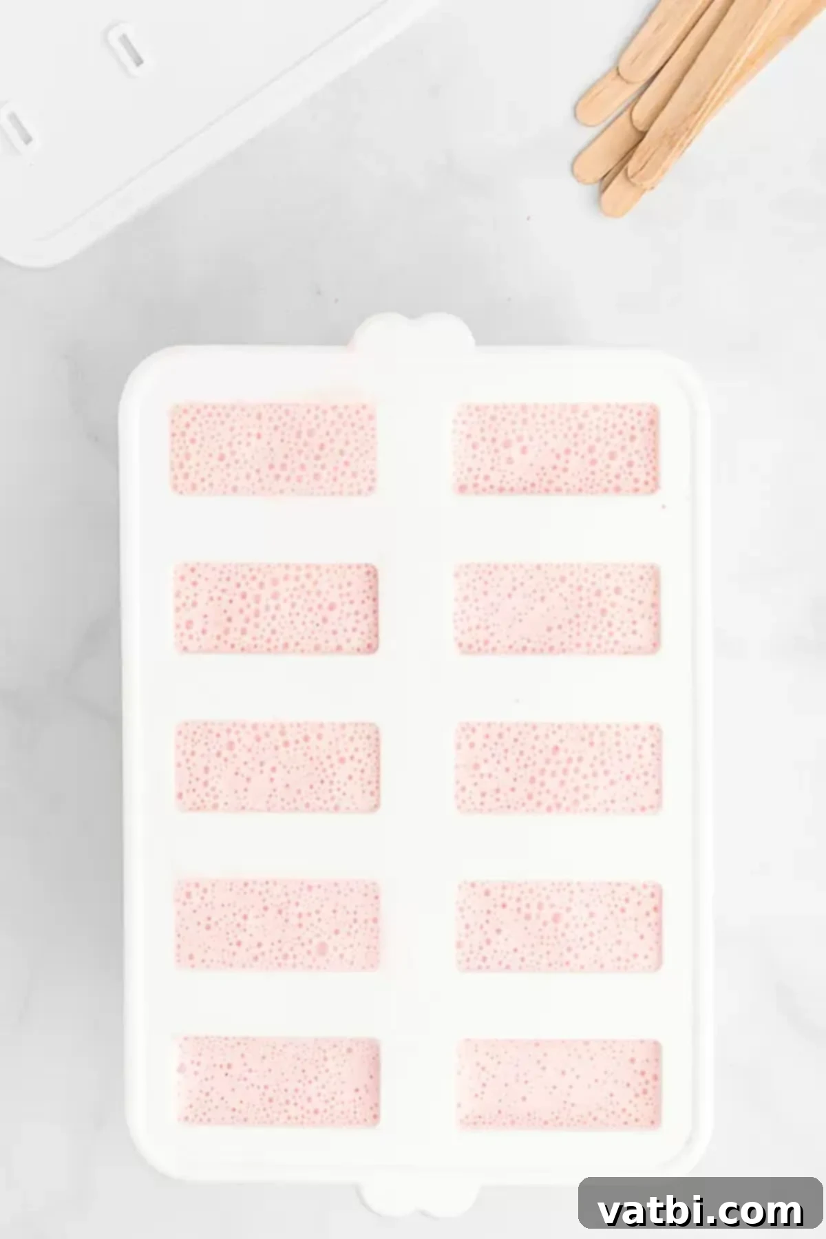 Refreshing Strawberry Yogurt Pops 5 Yogurt mixture in popsicle molds. Popsicle molds filled with a creamy strawberry yogurt mixture, ready for freezing.