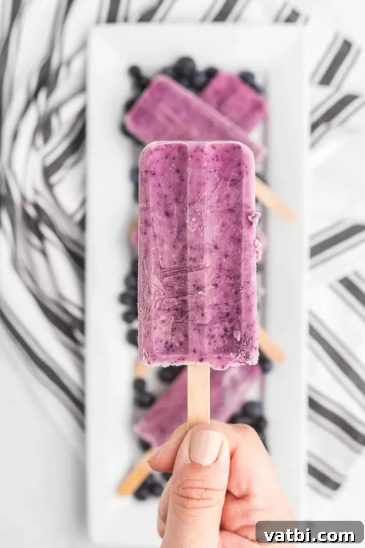 Berry Bliss Yogurt Pops 7 Close up photo of a single blueberry yogurt popsicle, showing its creamy texture