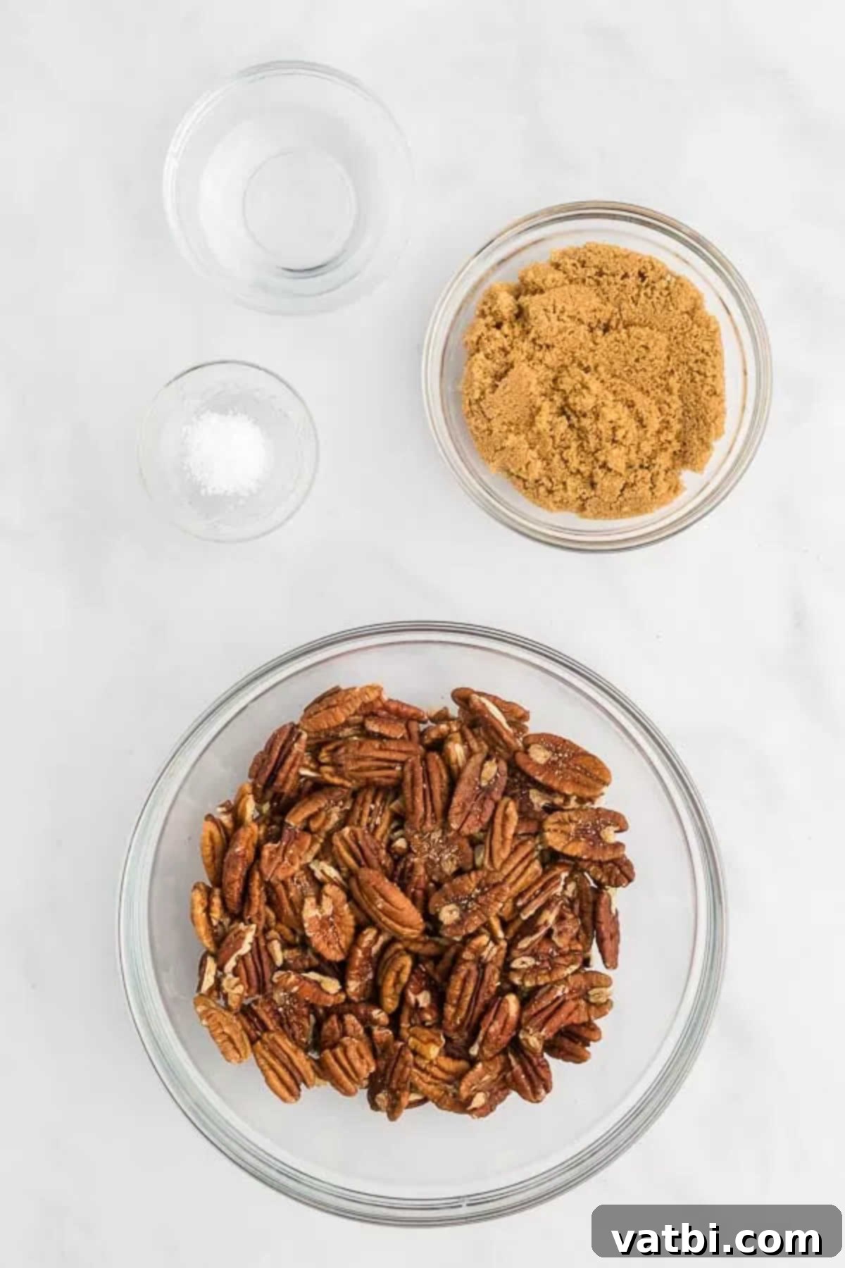 Ingredients for candied pecans: pecan halves, brown sugar, and salt, laid out on a clean surface.