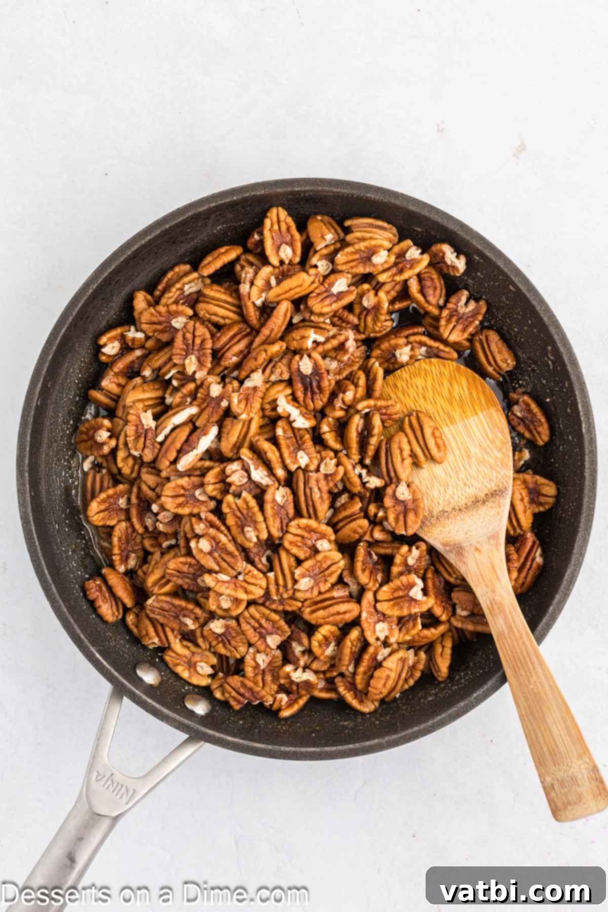 Pecan halves added to the bubbling brown sugar glaze, being stirred to coat evenly.