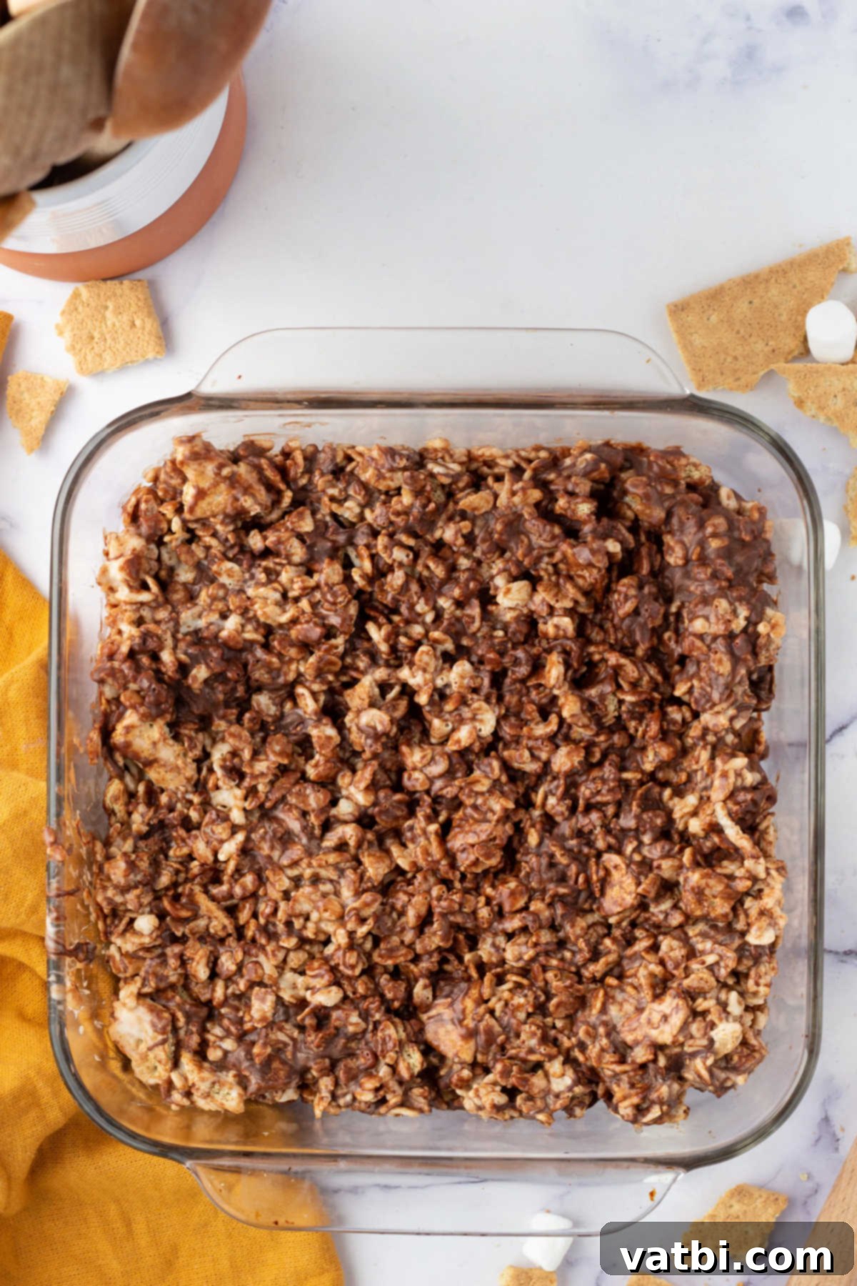 Campfire S'mores Rice Krispie Treats 6 The S'mores Rice Krispie treat mixture spread evenly into a parchment-lined baking pan, ready for chilling.