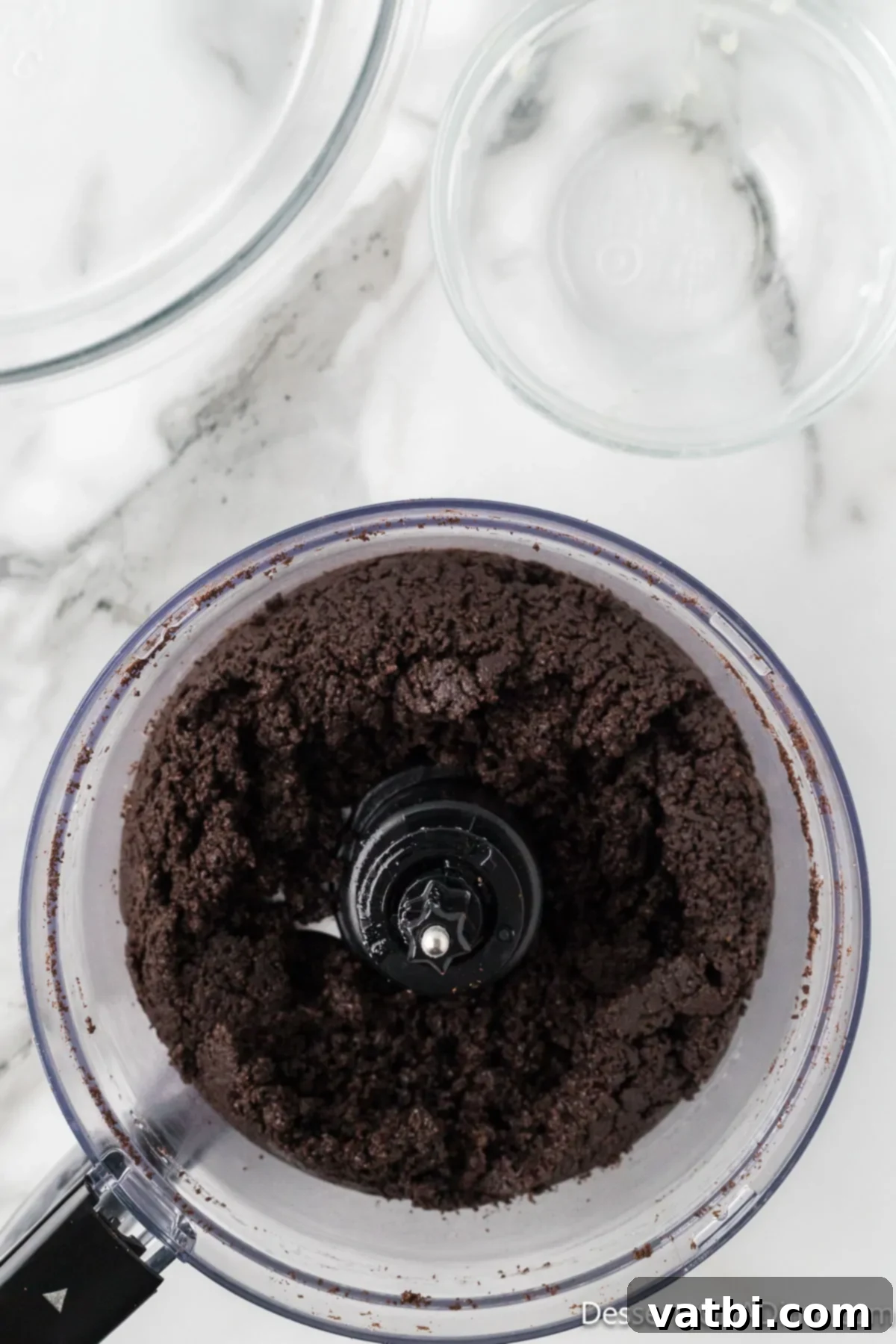 Effortless Oreo Indulgence 4 Oreo cookie crumbs thoroughly mixed with melted butter in a bowl.