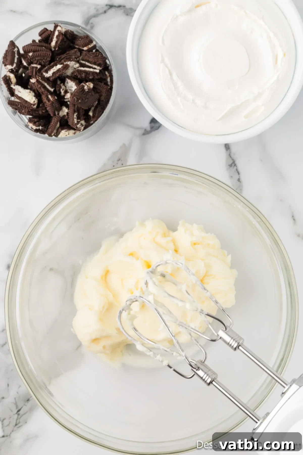 Effortless Oreo Indulgence 6 Mixing bowl with softened cream cheese and powdered sugar being beaten together.